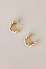 Side view of these earrings that feature gold hardware, rows of faux pearls, an open circle design, and secure post backings.