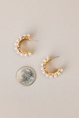 Size comparison of these earrings that feature gold hardware, rows of faux pearls, an open circle design, and secure post backings.