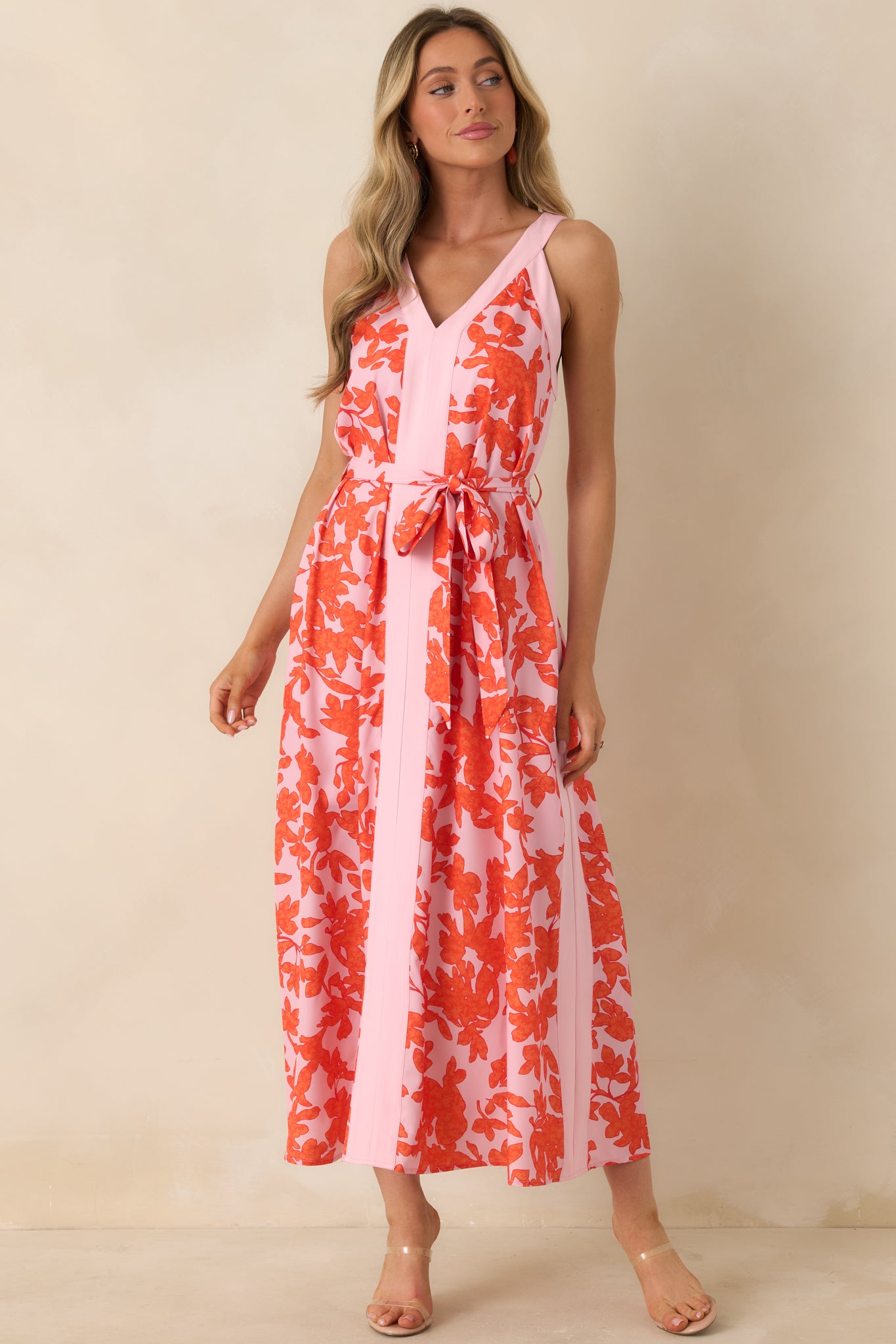 Dress featuring coordinating tie belt at waist, bold floral pattern, and graceful drape.