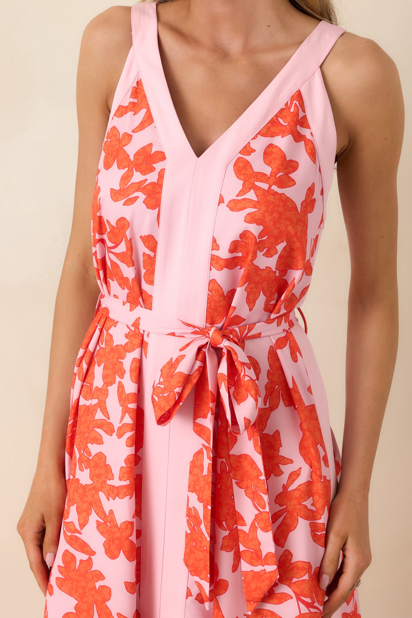 Close view of bold orange floral pattern, V-neckline, and tie belt detail on lightweight fabric.