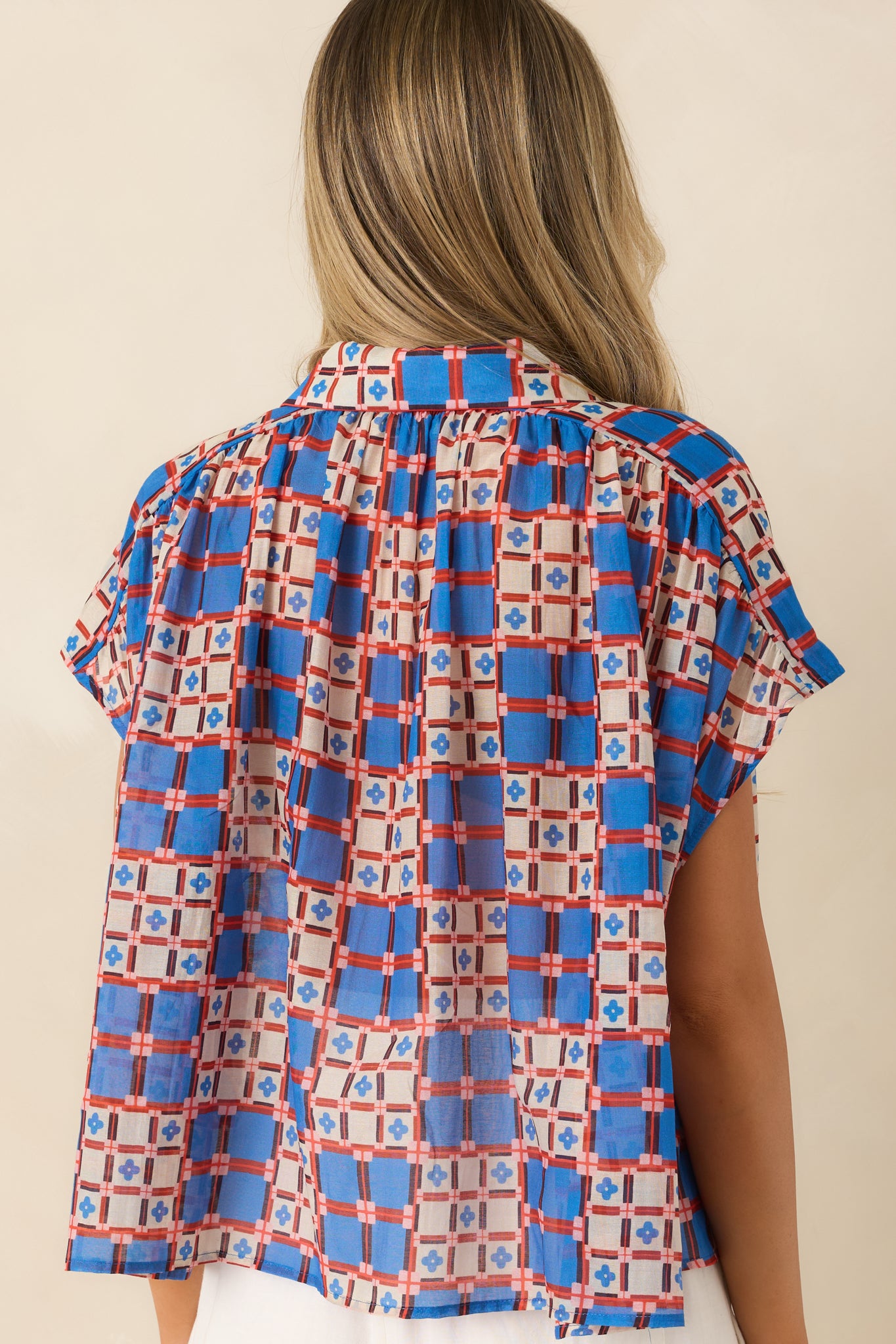 Rear view of sleeveless blouse with relaxed fit and lightweight sheer drape.