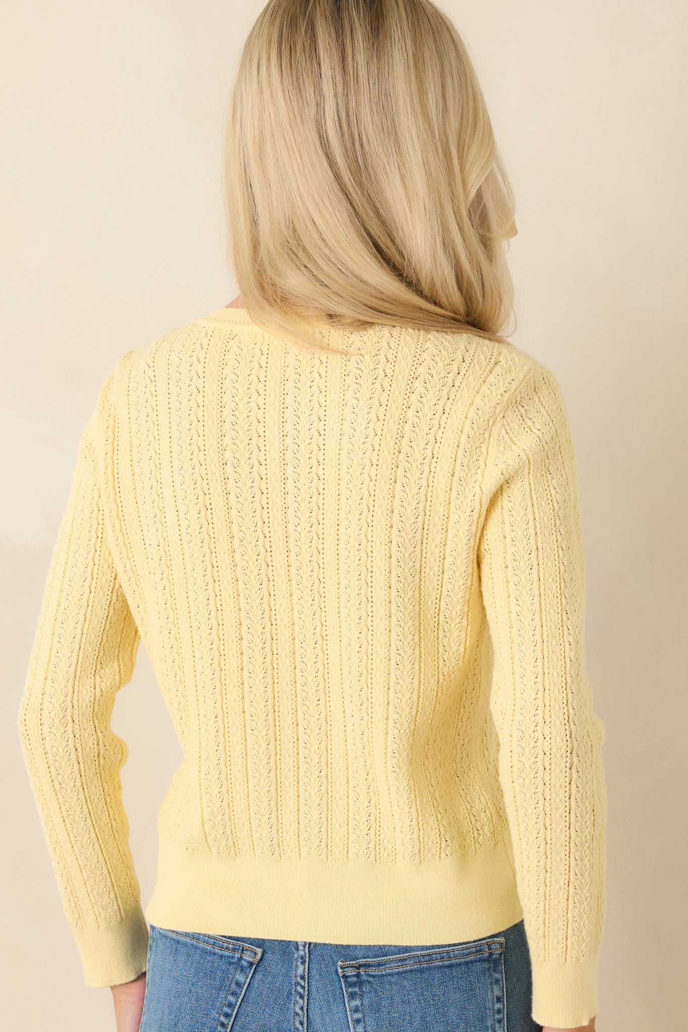 Rear view of butter yellow cardigan with cropped silhouette and breathable knit design.