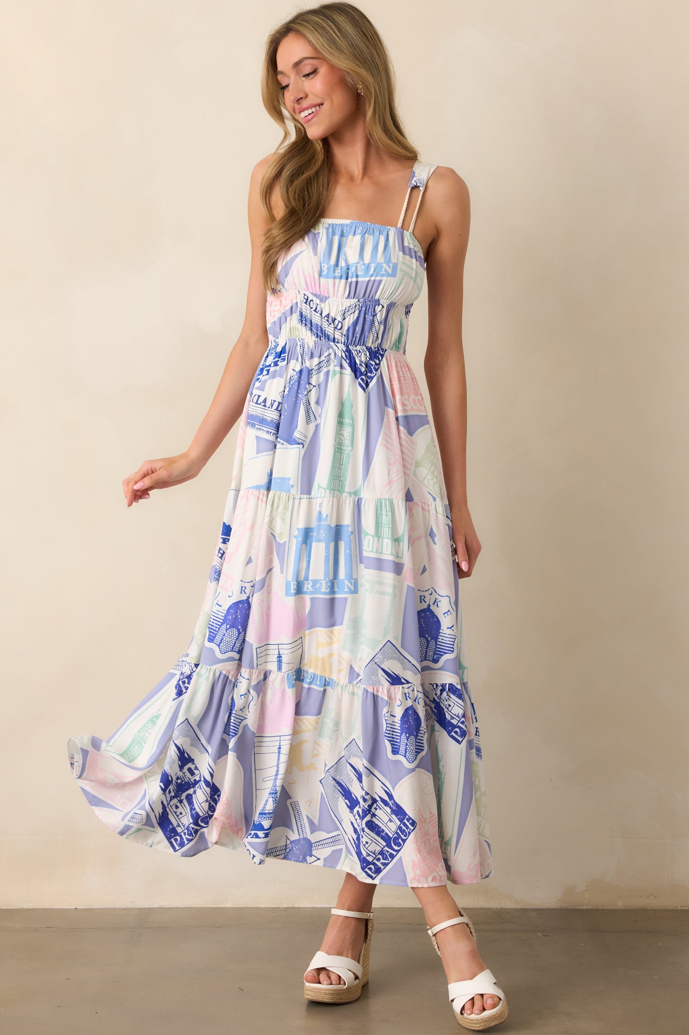 A stylish blue midi dress with a smocked panel, elastic waistbands, and a travel-themed print for a breezy, comfortable fit.