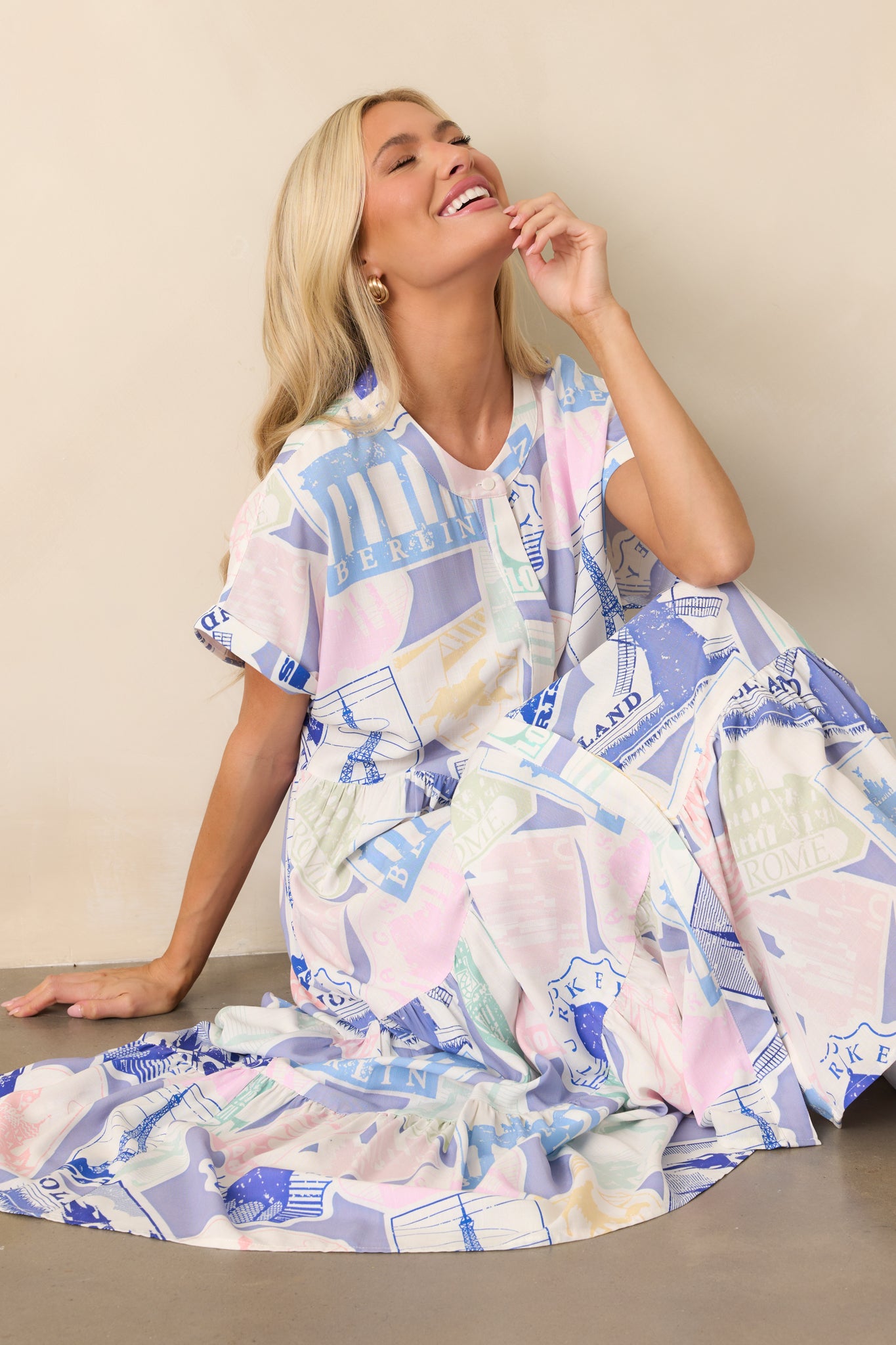 A blue midi dress with a passport-inspired print, featuring a round neckline and a tiered silhouette for a flowing fit.