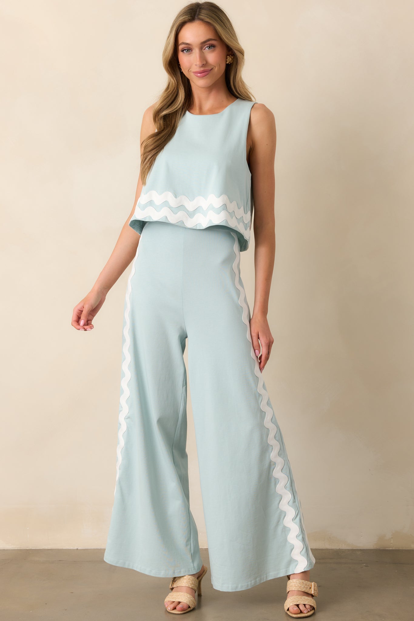 A vibrant blue jumpsuit with a structured silhouette, highlighted by a tiered bodice and decorative white ric rac trim.