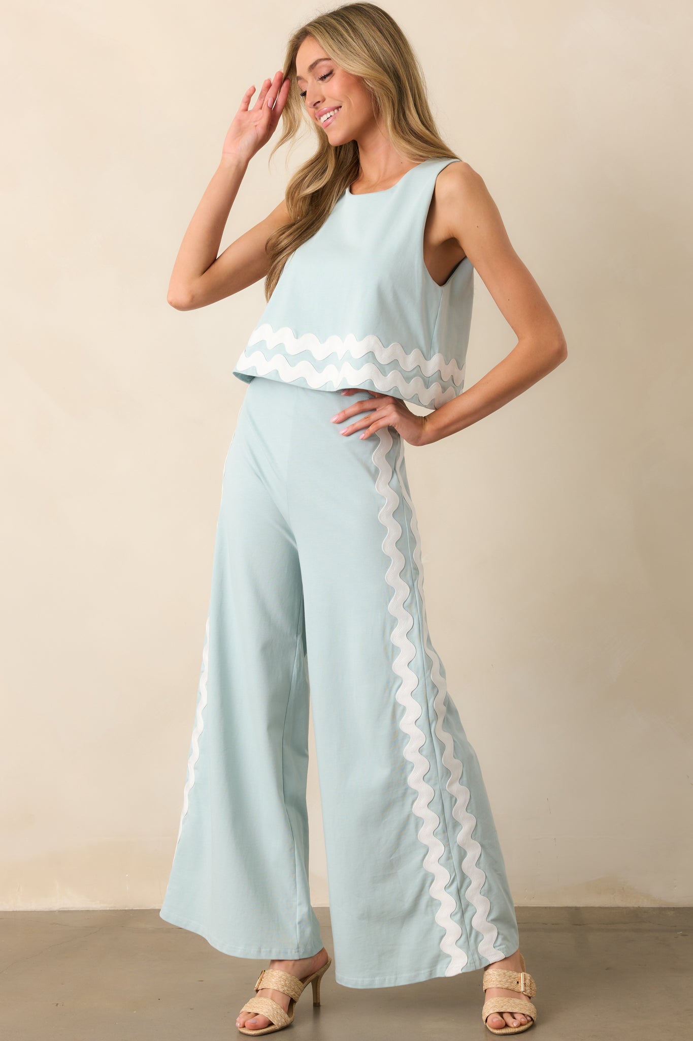 A stylish blue jumpsuit with a hidden zipper closure, a layered top effect, and delicate white ric rac trim along the edges.