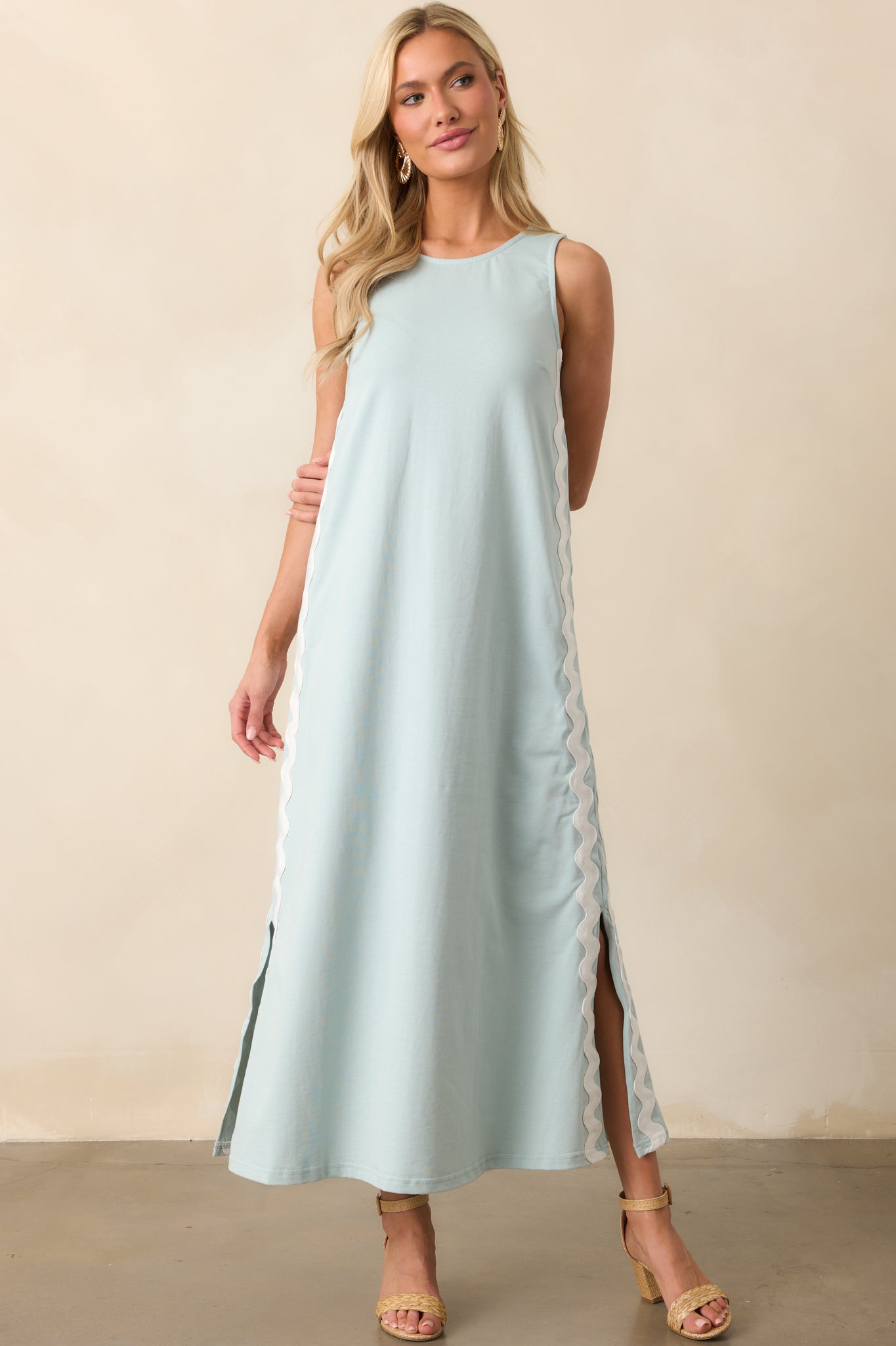 A blue maxi dress featuring a round neckline, sleeveless design, and white ric rac trim running vertically down both sides.