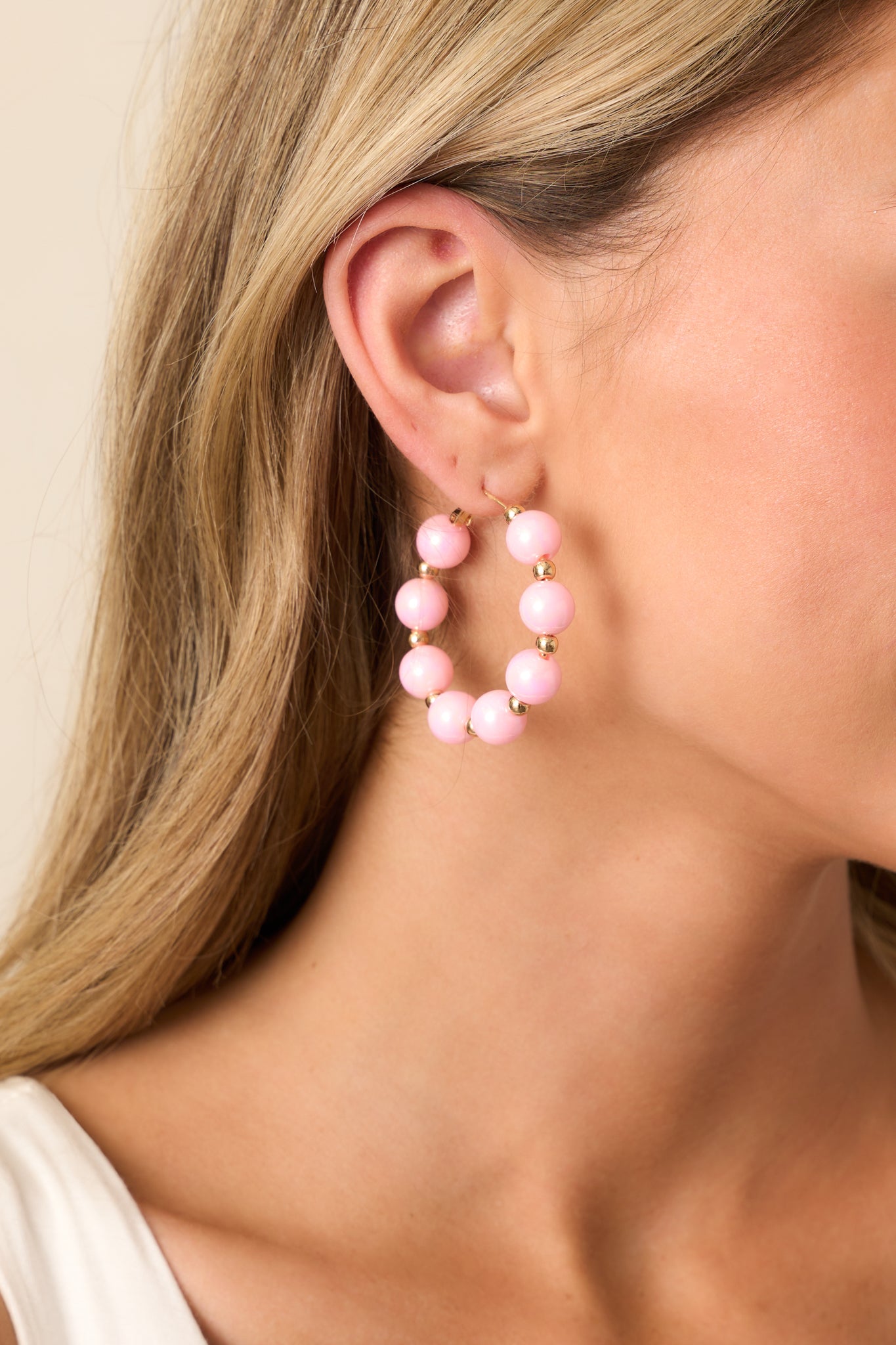 A closer look at the lustrous pink beads and polished gold details that make these hoop earrings effortlessly stylish.