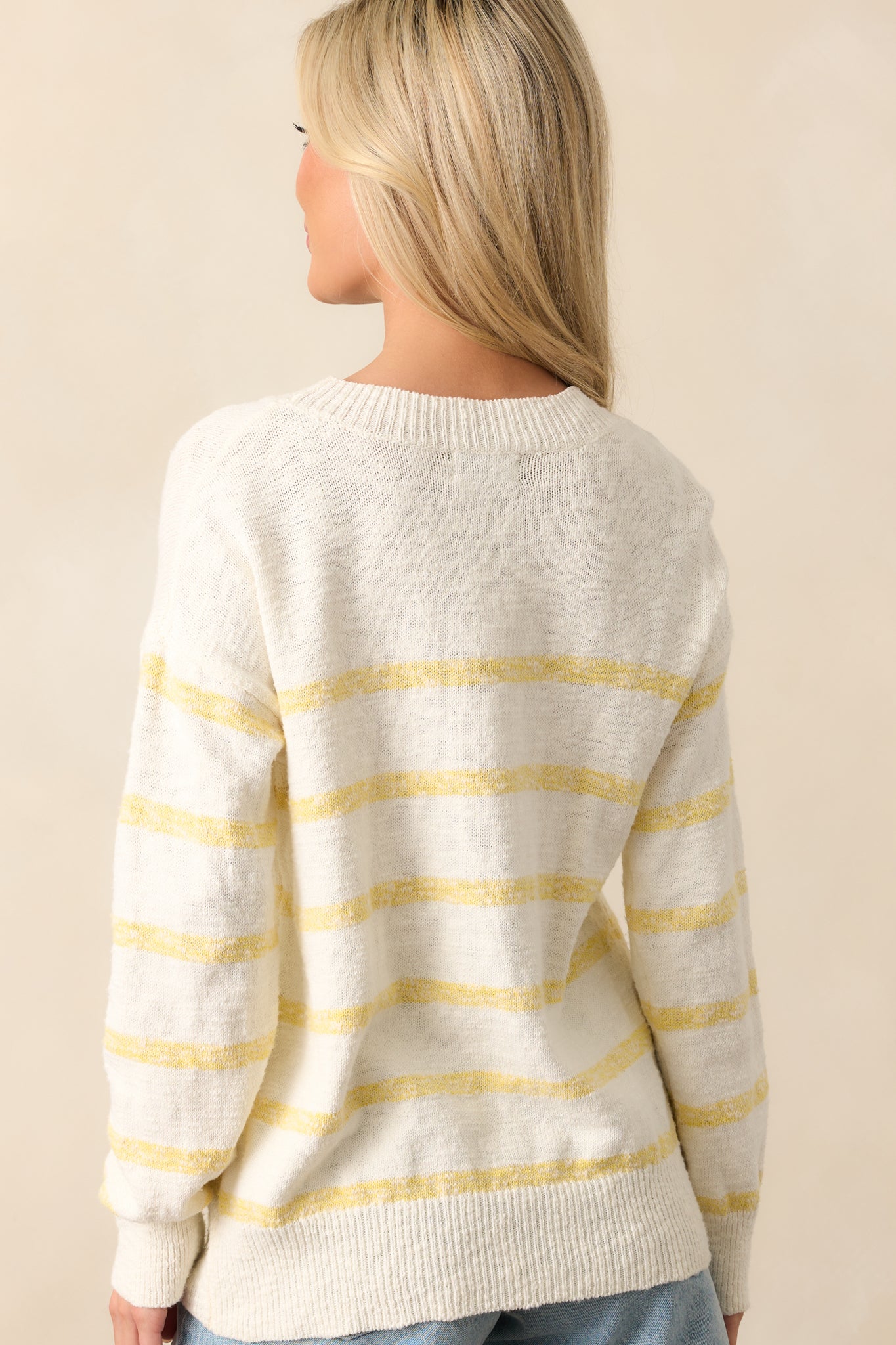 A rear view of the ivory sweater, displaying the lightweight fabric and continuous stripe design.