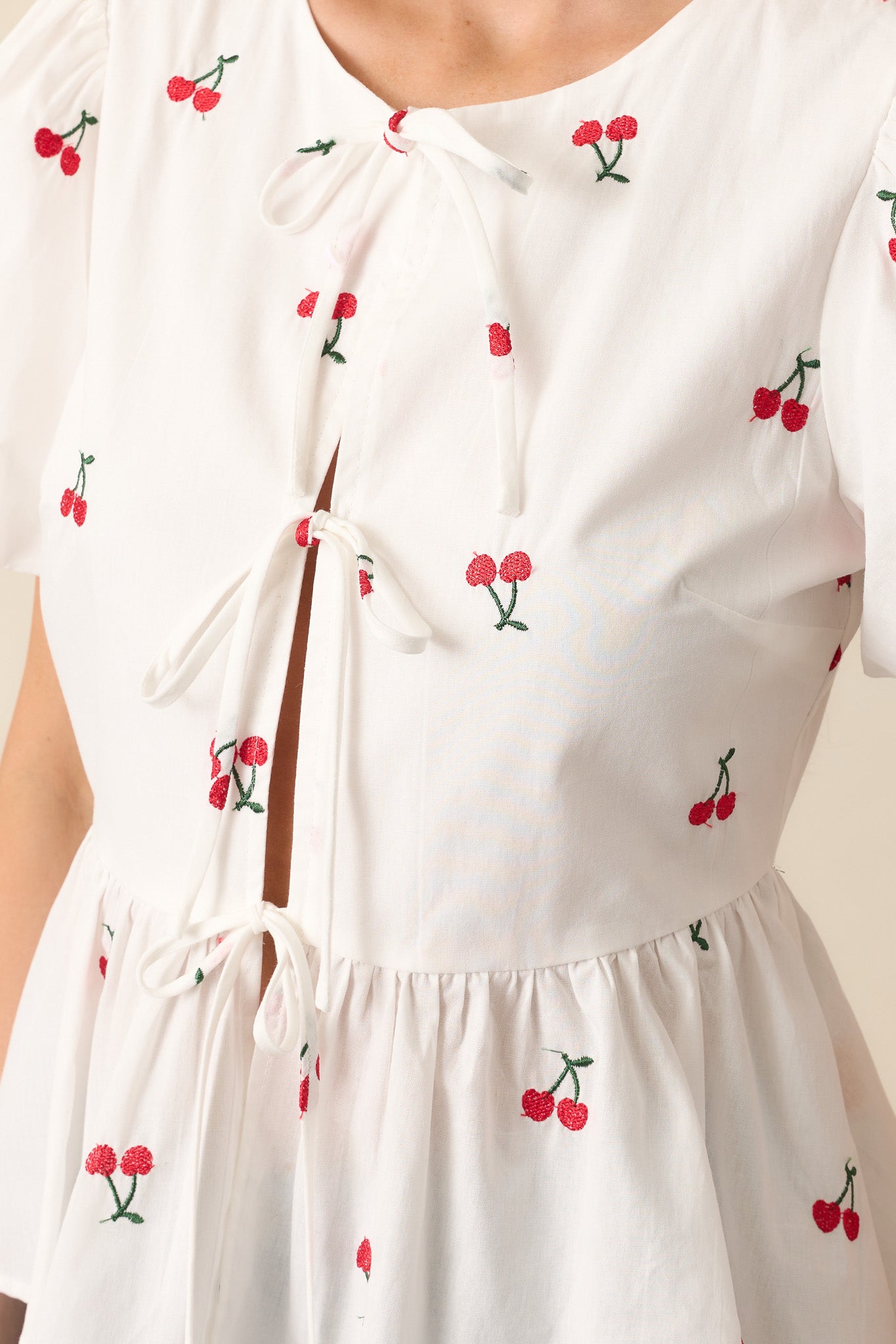A zoomed-in view of the embroidered cherries, showcasing the intricate stitching, dainty self-tie bows, and soft fabric texture.