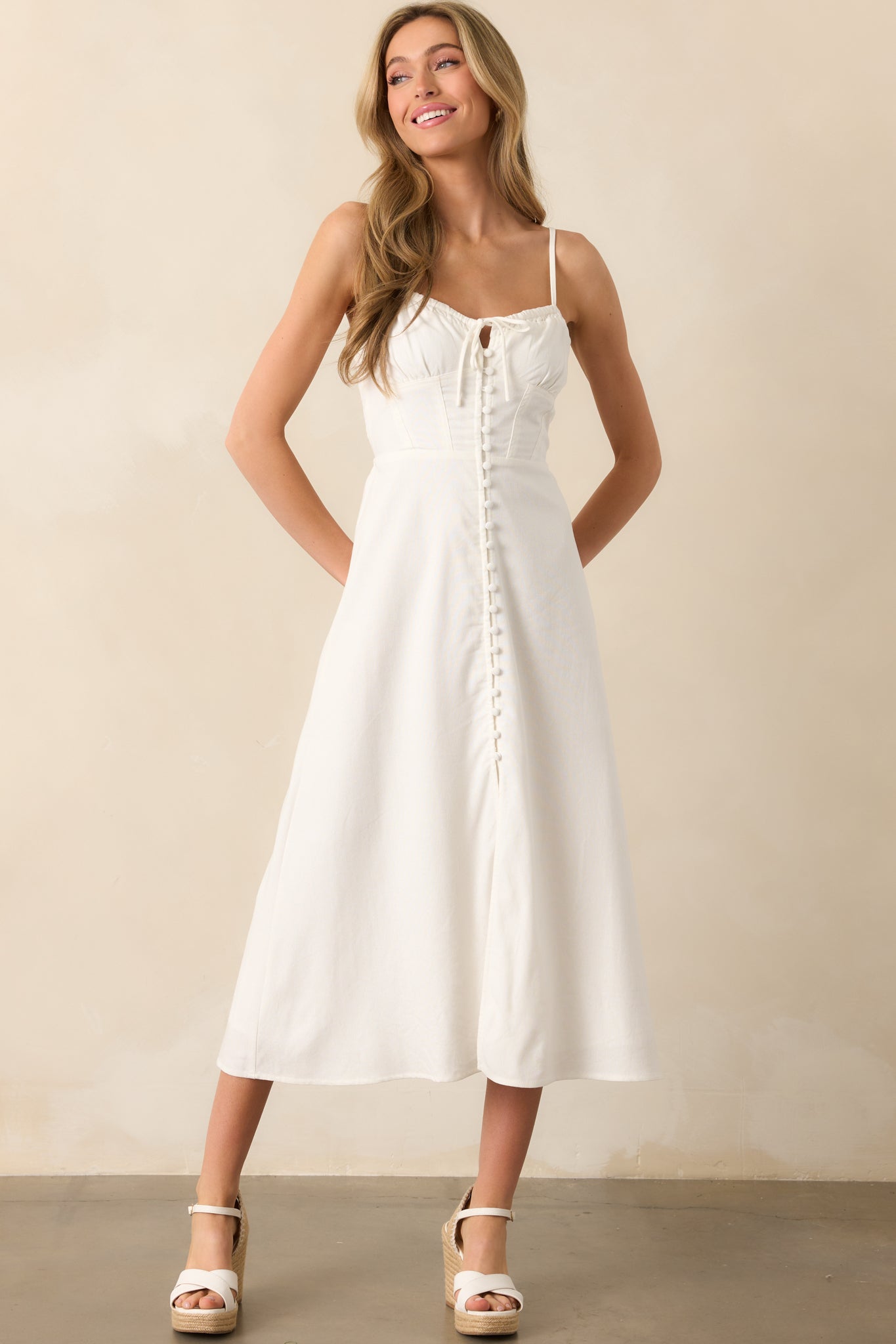 Direct front image of an ivory dress highlighting its refined corset design with a functional button front and adjustable straps.