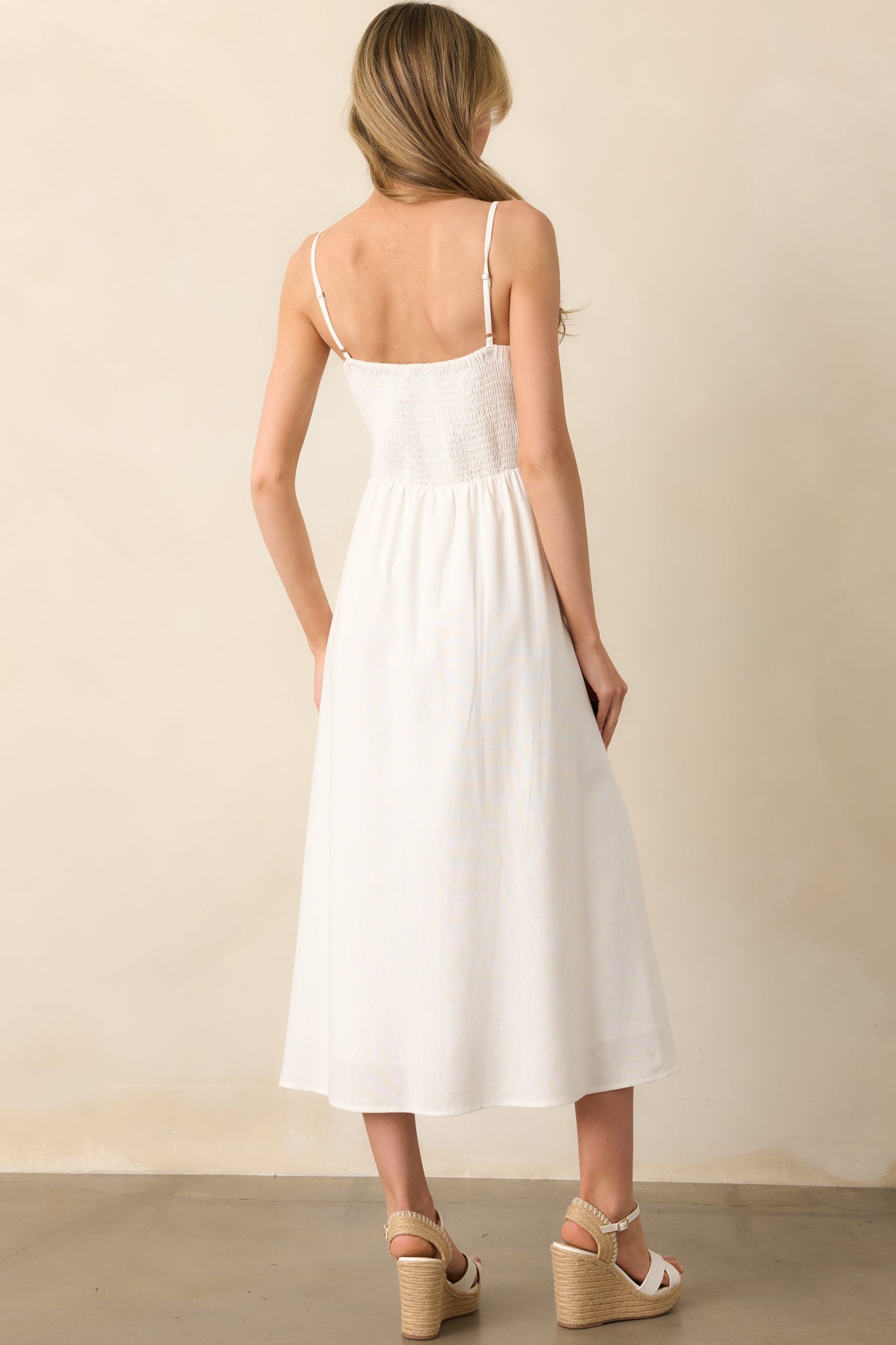 A view from behind of the ivory dress highlighting the smocked back panel and adjustable straps.