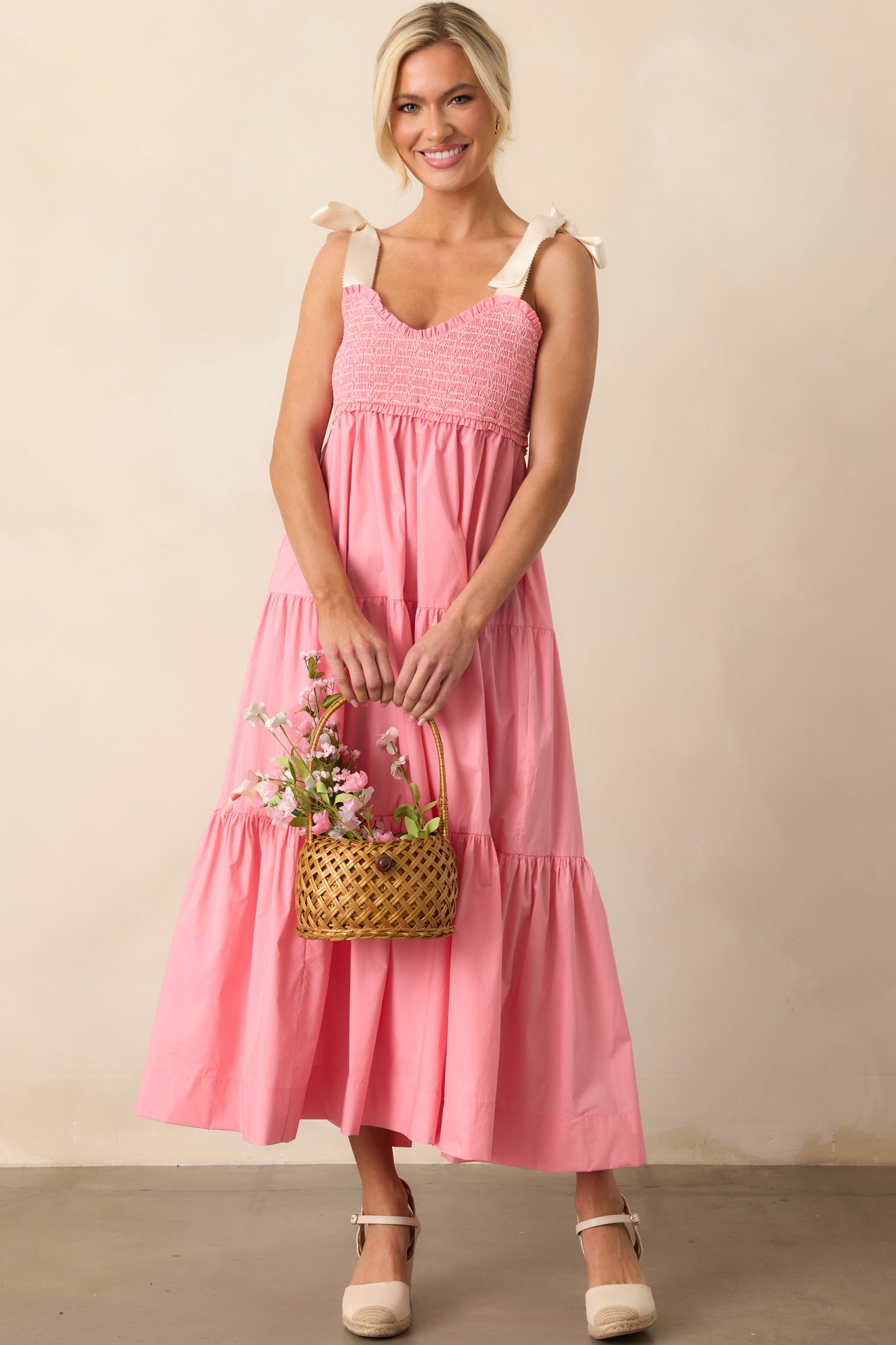 The pink coral midi dress showcases its smocked bust with delicate white embroidery, dainty ivory self-tie straps, and a flowy silhouette with pockets.
