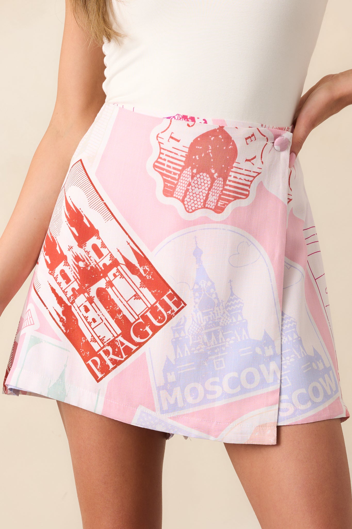A detailed look at the travel-inspired print on the pink skort, showcasing passport stamps and travel motifs across the fabric.