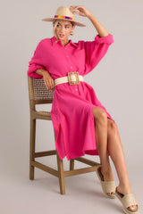 Angled full body view of this dress that features a collared neckline, functional buttons down the front, a front pocket on the left side of the bust, long sleeves with a cuff secured by a functional button, and two slits up the bottom hemline ending just below the knee.