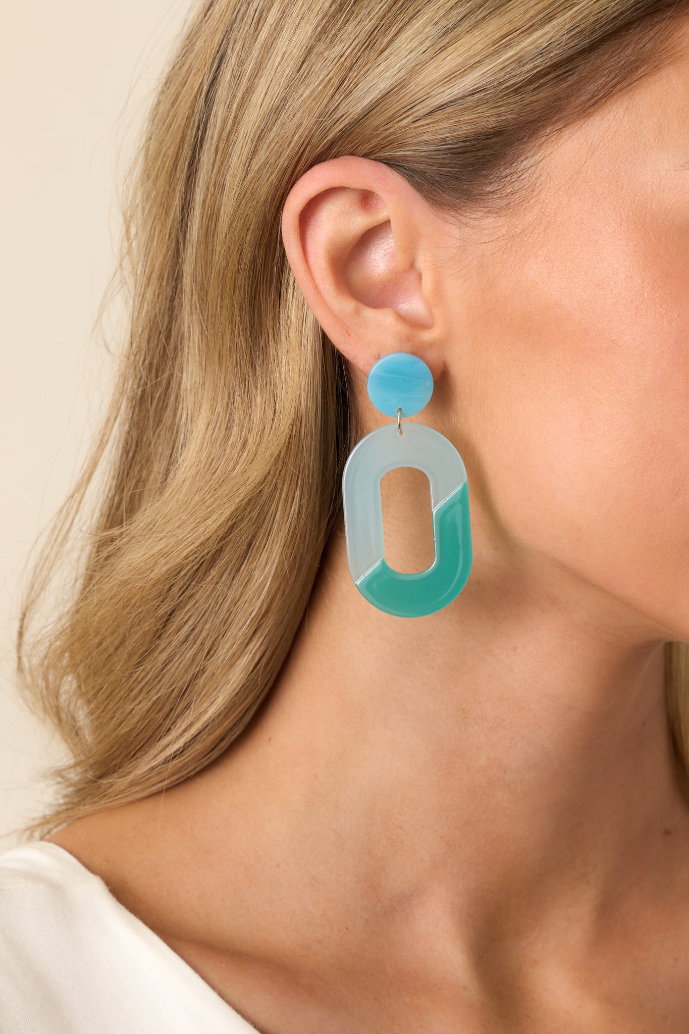 A partial view of the blue and teal acrylic earrings, highlighting the ombre acrylic circular stud.