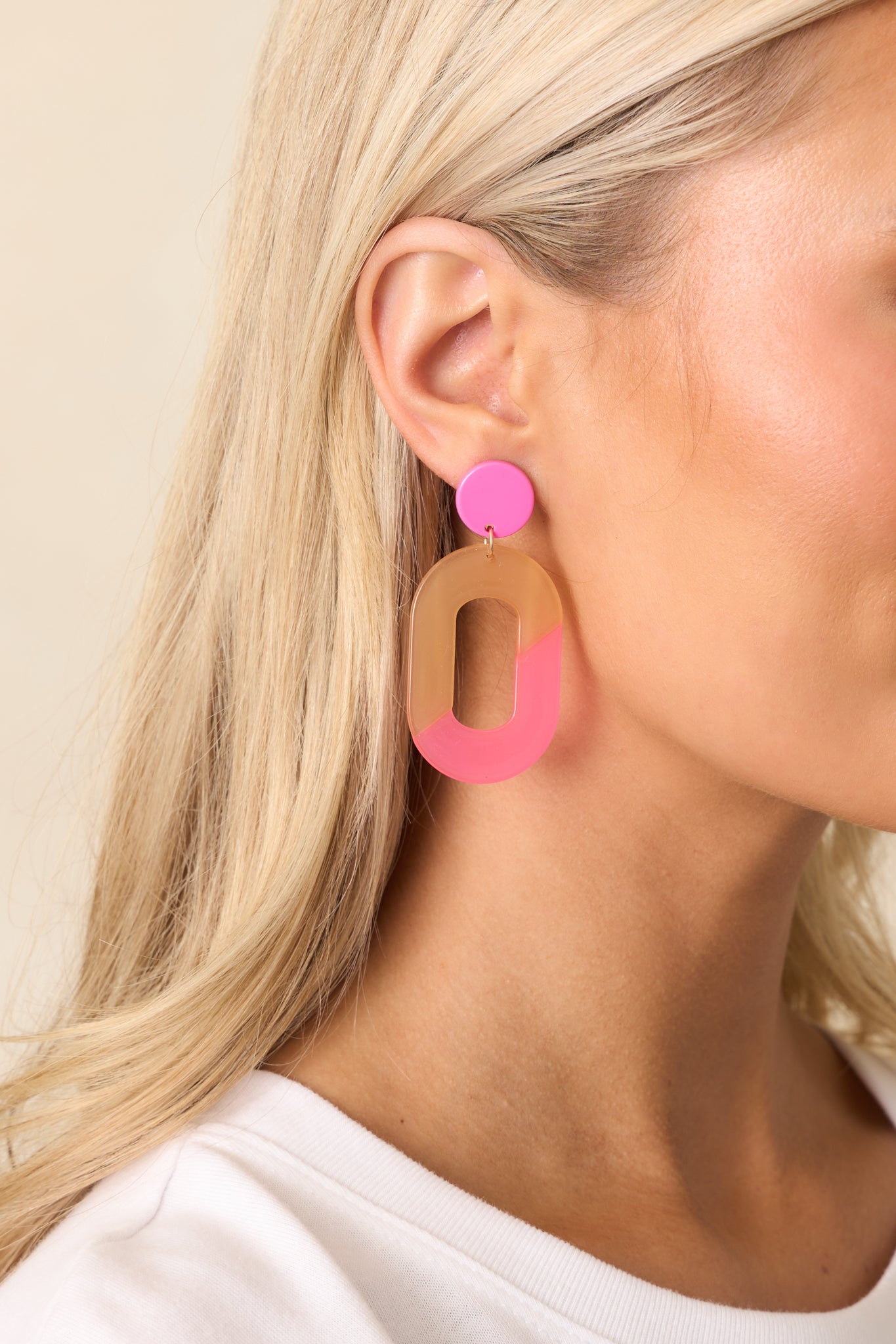 A partial view of the pink and peach acrylic earrings, highlighting the ombre acrylic circular stud.