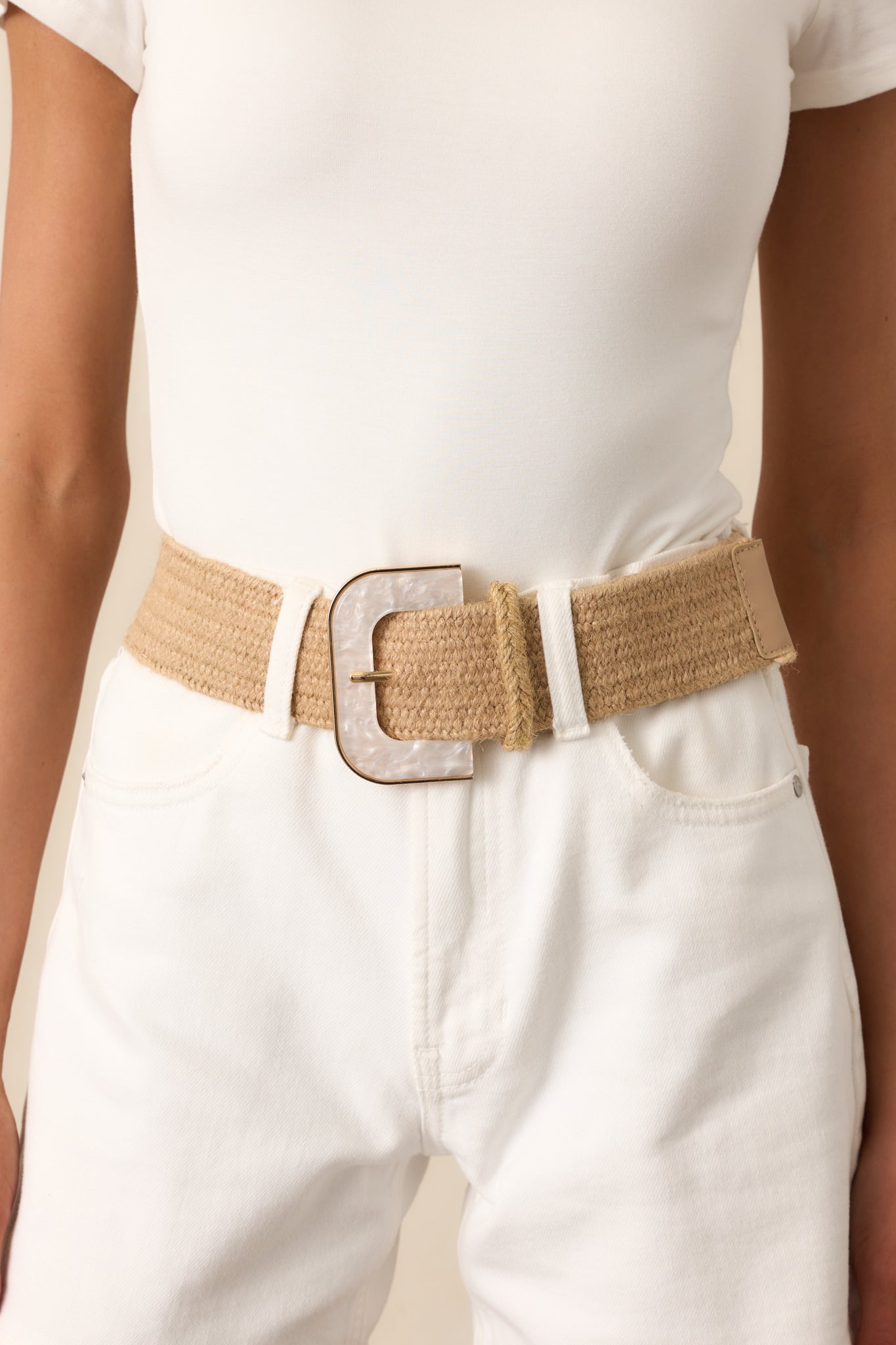A partial view of a tan woven belt, showing the iridescent faux marble buckle with gold trim.
