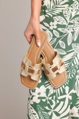 These gold sandals feature a square toe, a slip-on design, and a strap with cutouts over the top of the foot.