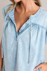 Close up view of this dress that features a v-neckline, a self-tie feature, gathering in the bust, a thick seam down the front and back, functional hip pockets, and wide cuffed short sleeves.
