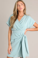 Front view of this dress that features a v-neckline, an elastic waist insert, a self-tie wrap feature, and wide cuffed short sleeves.