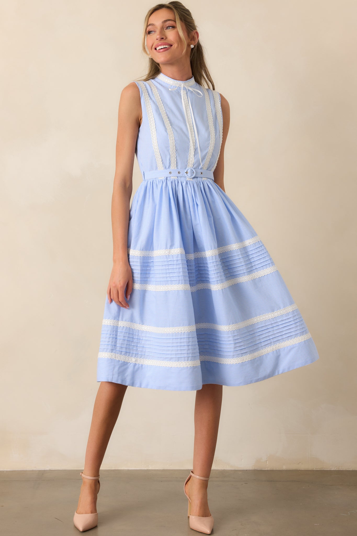 A charming midi dress with a hidden back zipper closure, mock neckline with bow detail, and a relaxed fit in a micro-gingham pattern.