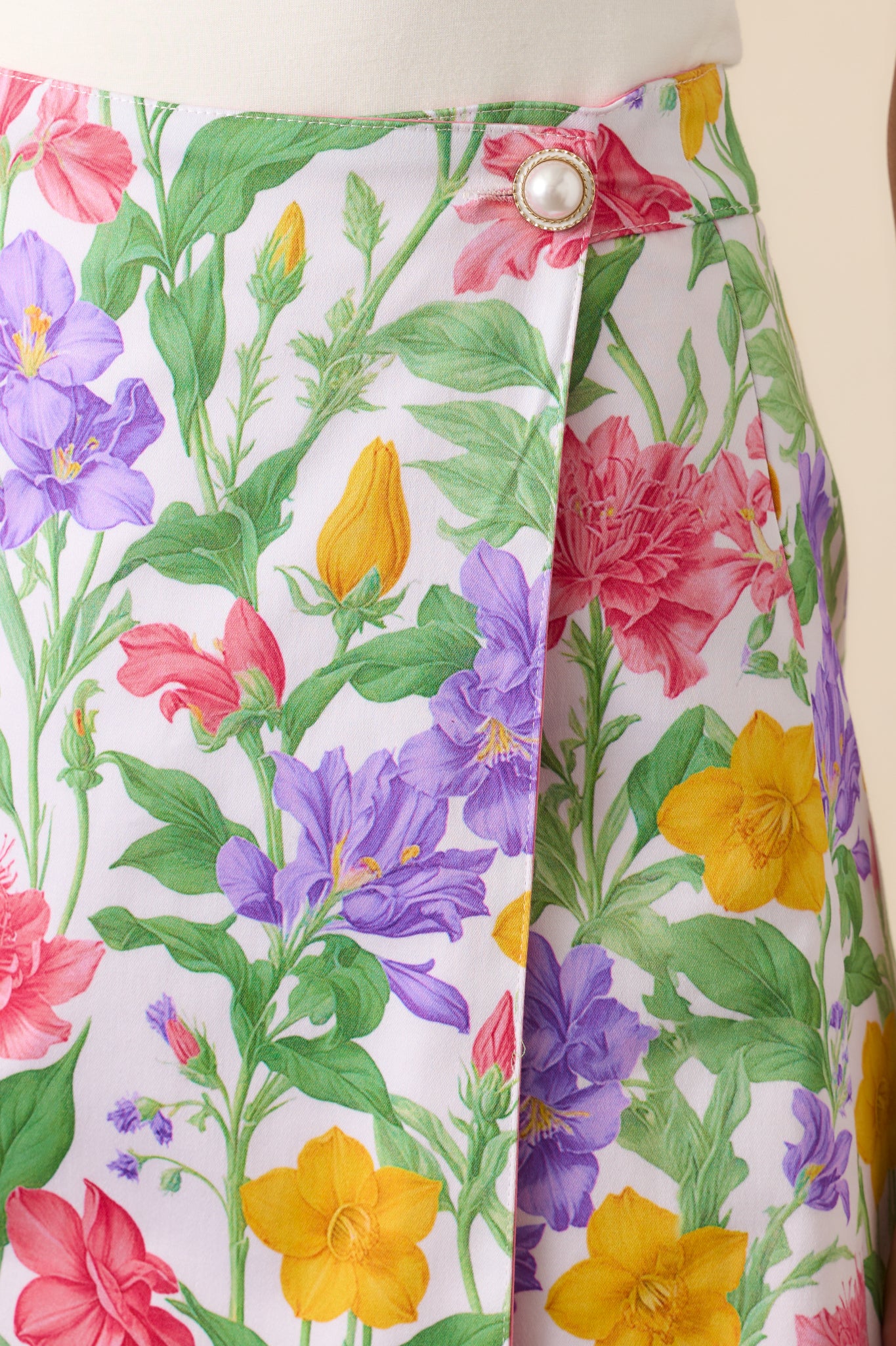 A close-up of the pearl top button at the waist, highlighting the functional and elegant detail of the reversible skirt.