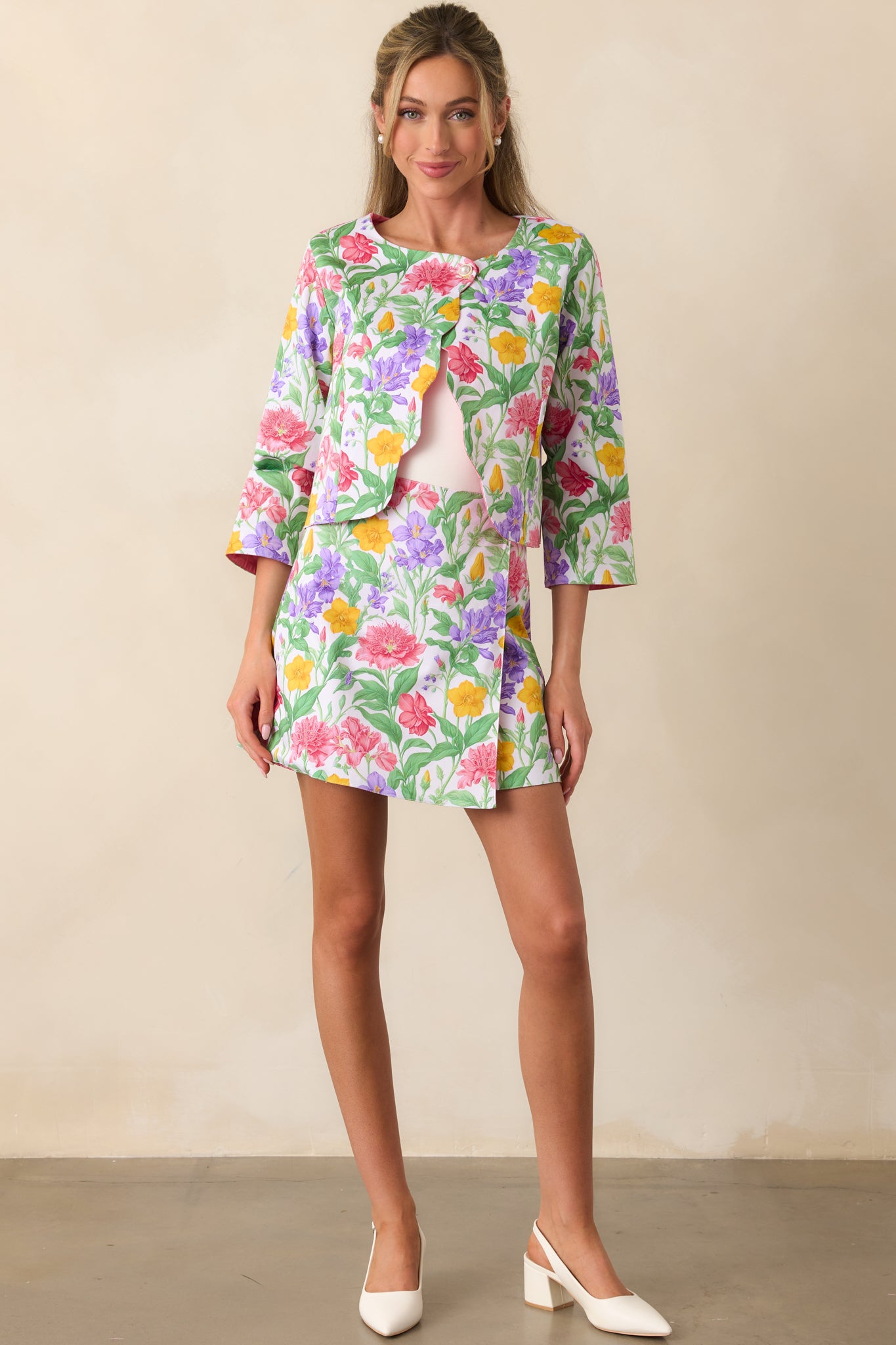 A front-facing view of the reversible mini skirt, showcasing the floral print side, wrap style design, and pearl button at the waist for added detail.