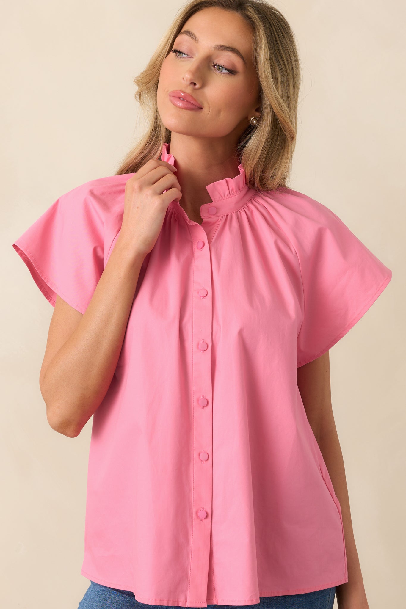 A zoomed-in view of the functional button front, showcasing the buttons and smooth, lightweight fabric of the geranium pink top.
