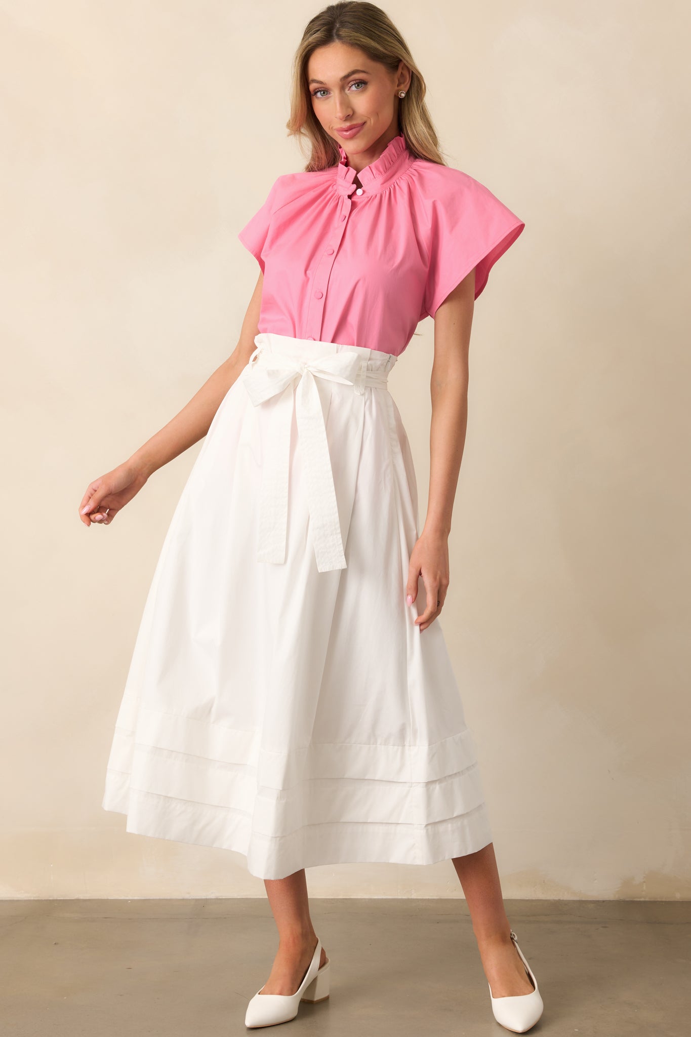 White midi skirt with functional belt loops, an optional self-tie belt, pleated detailing, and small tiers at the bottom, offering a flattering A-line silhouette.