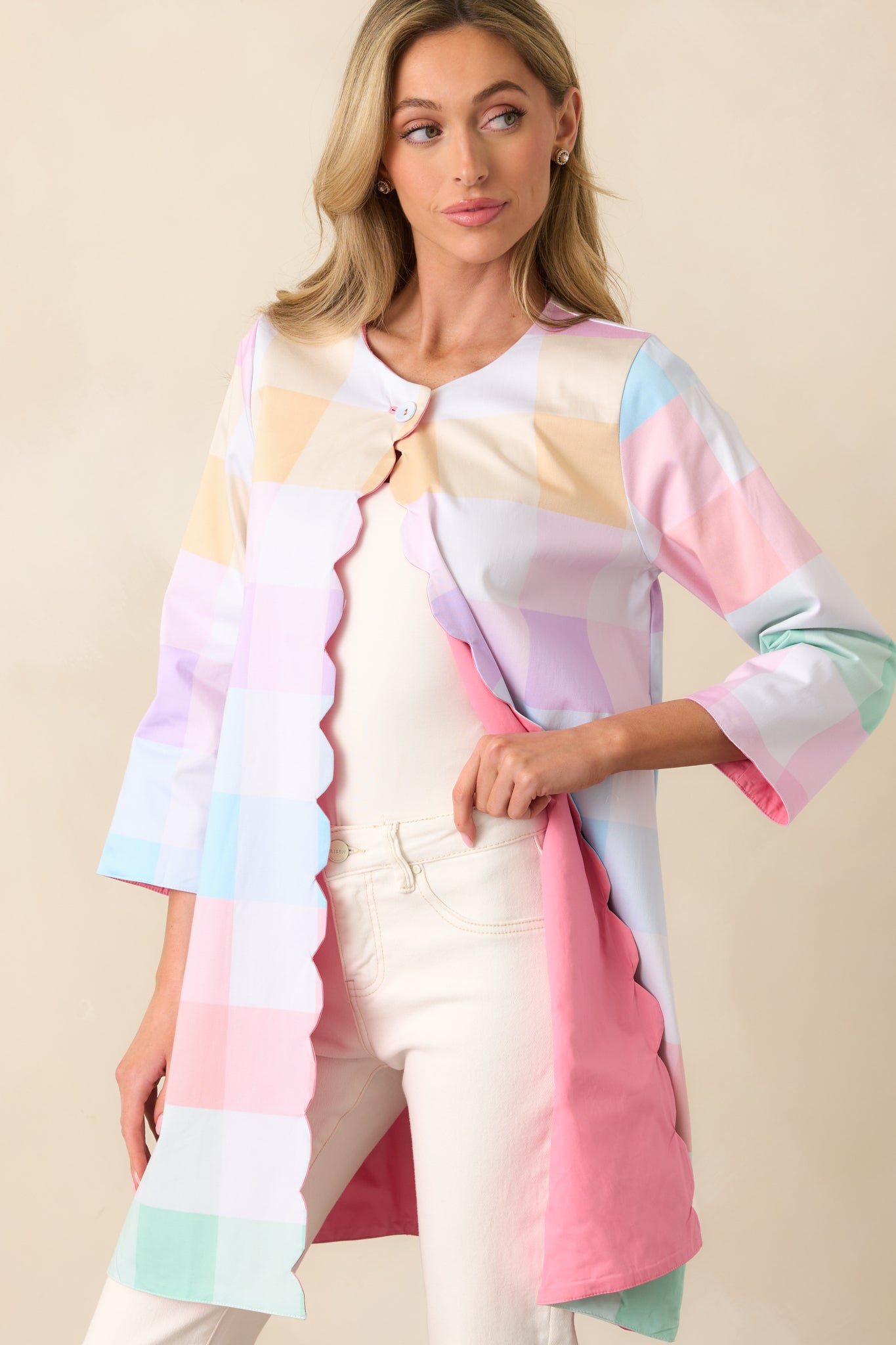 A pastel plaid jacket with 3/4 length sleeves, a functional top button closure, and scalloped detailing along the hem for a delicate finish.