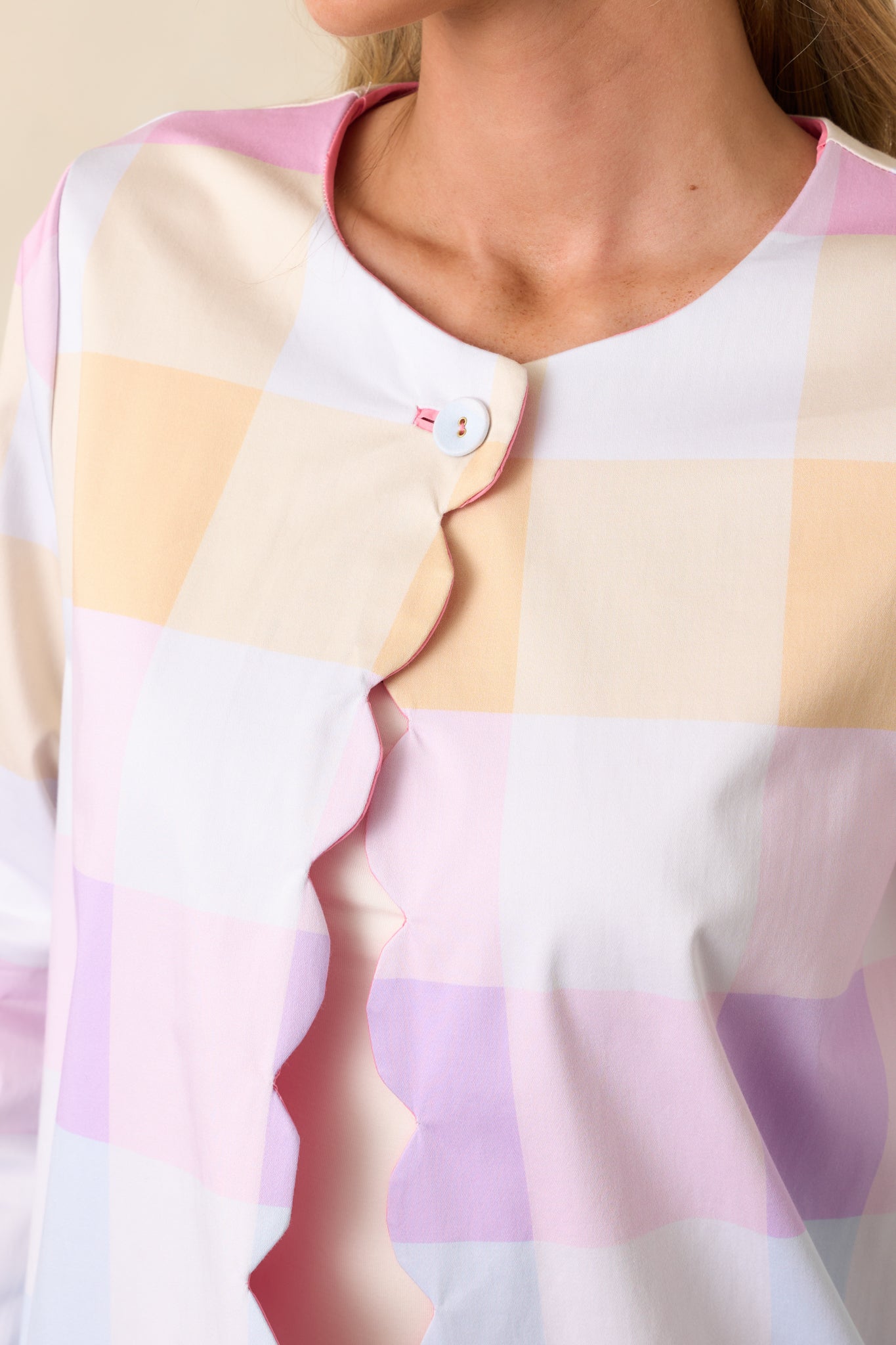 A zoomed-in view of the functional top button on the pastel plaid side, highlighting the intricate scalloped edge and precise stitching.