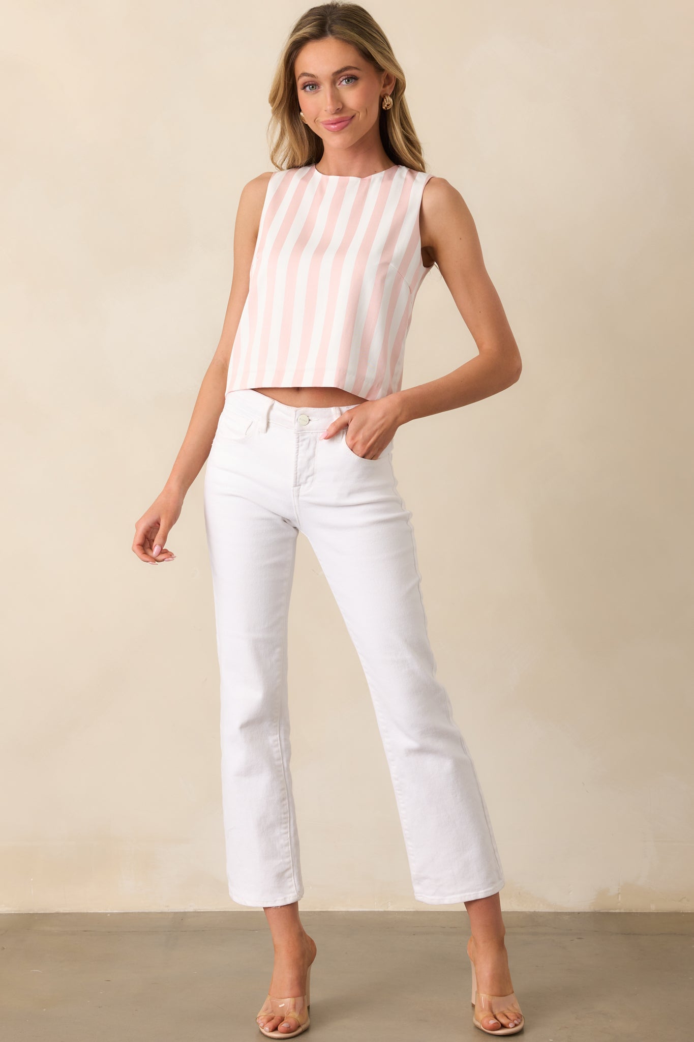 Striped top with a light pink and white pattern, featuring a round neckline, sleeveless cut, and slightly cropped length for a stylish, modern fit.