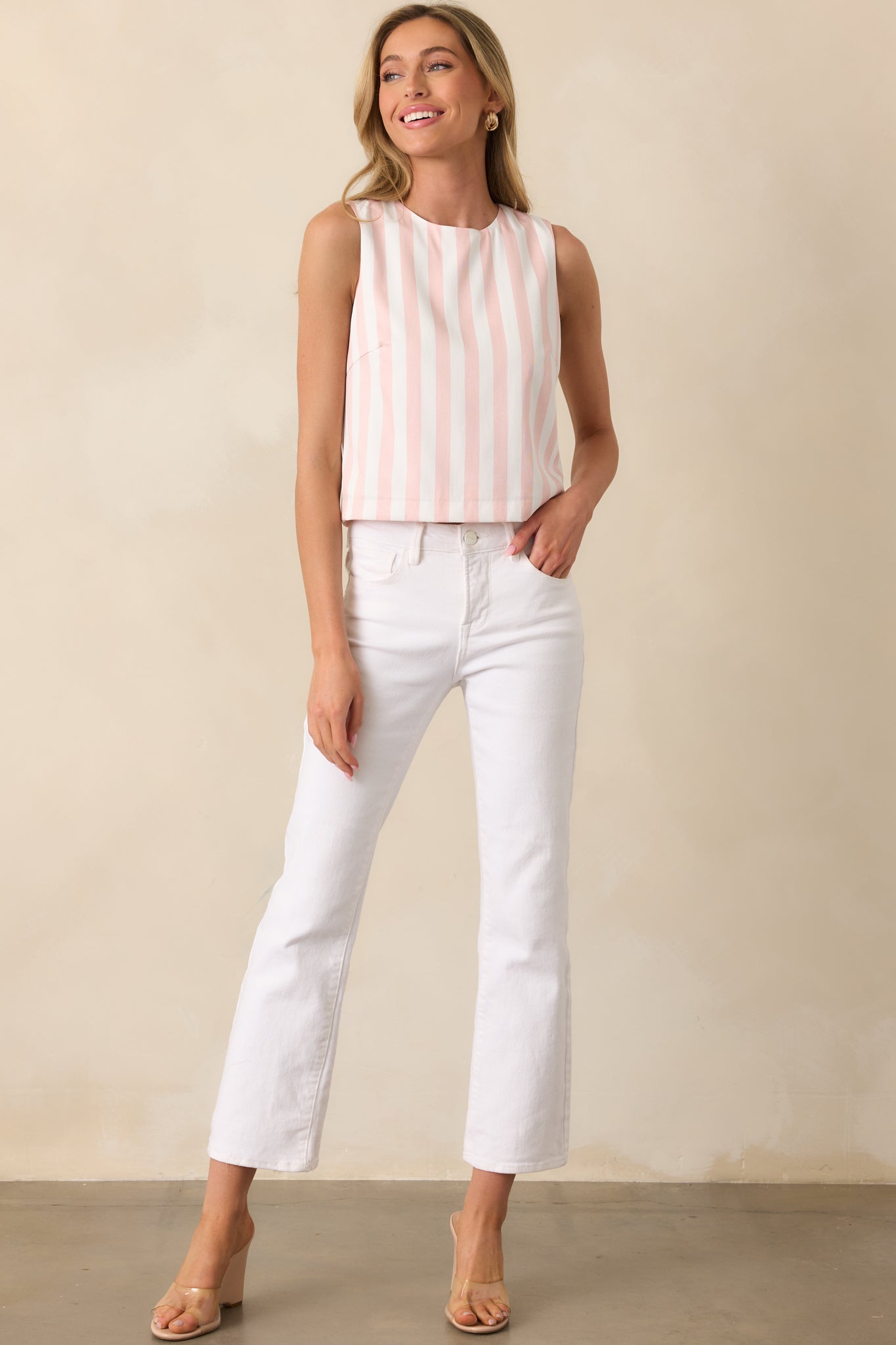 Striped top with a light pink and white pattern, featuring a round neckline, sleeveless cut, and slightly cropped length for a stylish, modern fit.