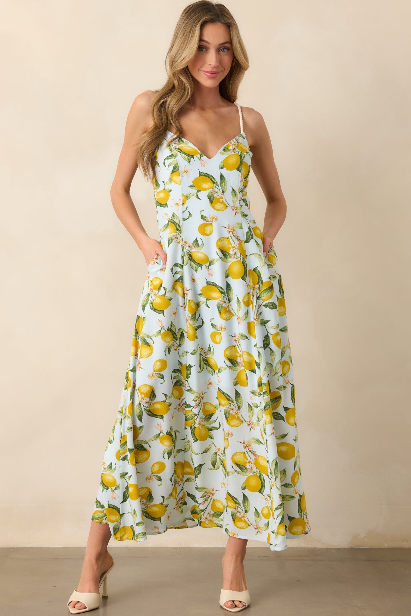 Front-facing full length image of lemon-printed dress highlighting adjustable tassel-end straps and fitted bodice.