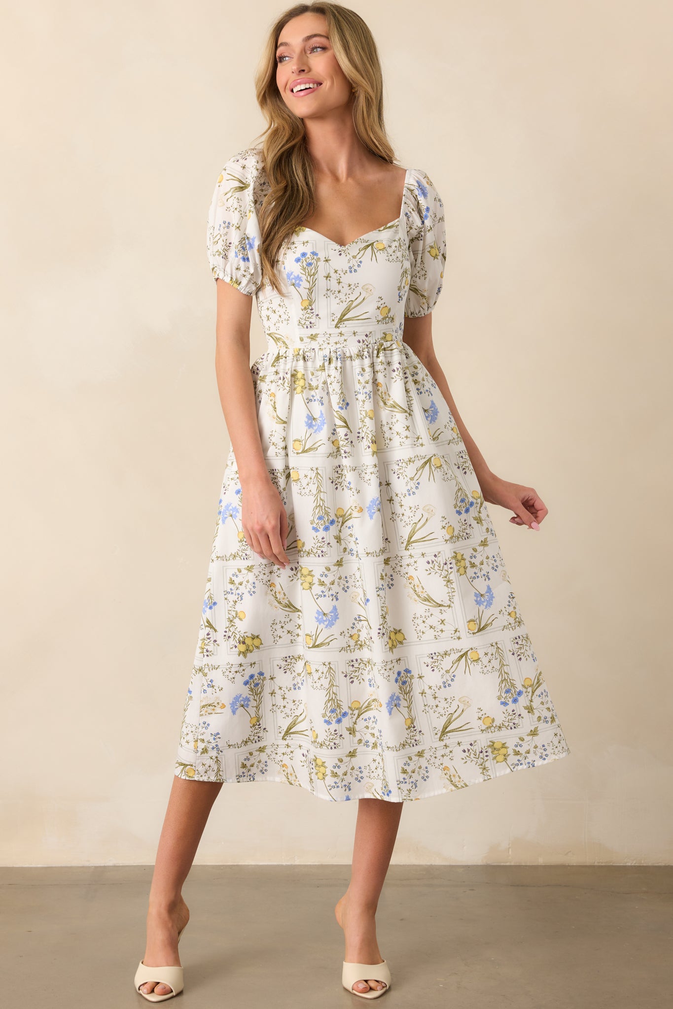 Front view of a white floral midi dress featuring puff sleeves with elastic cuffs and a fitted bodice.