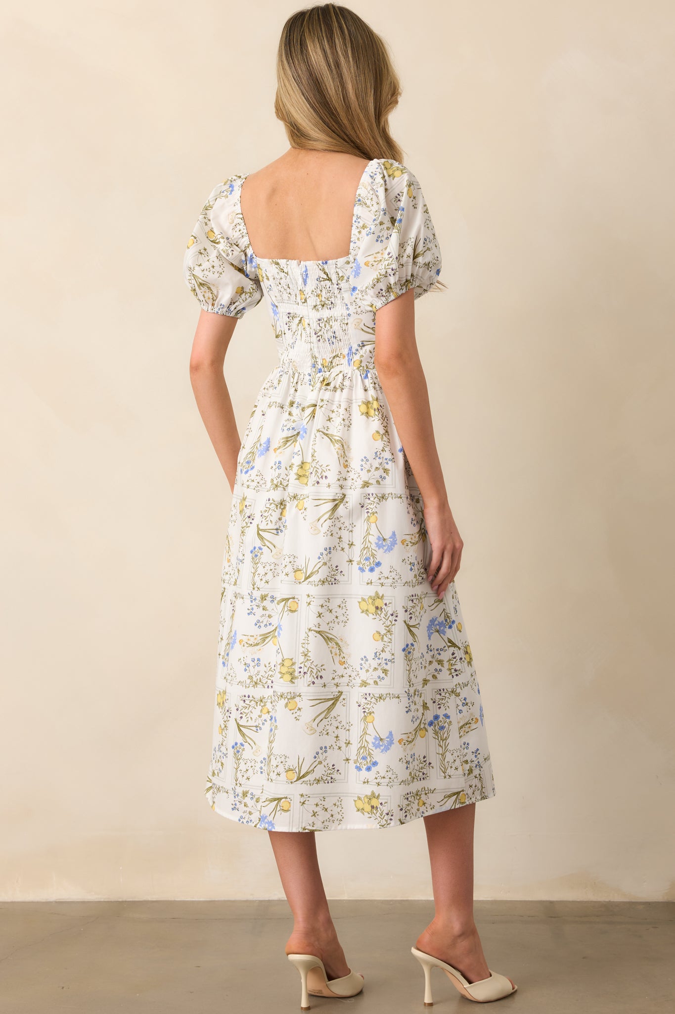 Rear view of the dress showing smocked back panel, hidden zipper, and continuation of the lemon floral print.