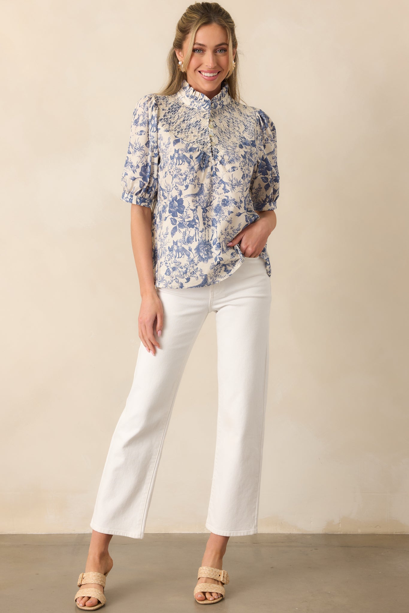 Blue toile print top featuring a mock ruffle neckline, smocked embroidered yoke, and a functional 1/4 button front.