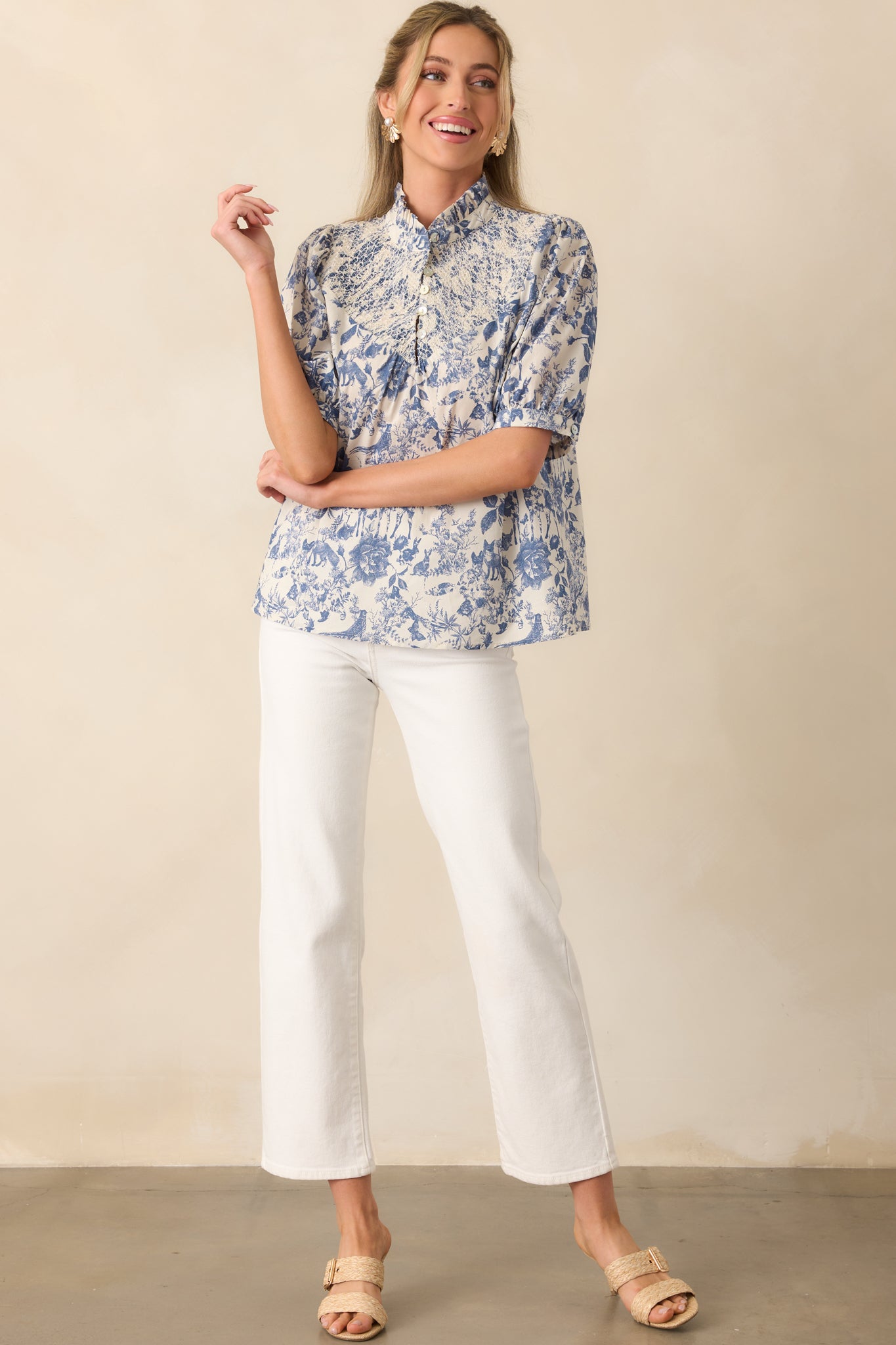 Elegant blue top with a delicate toile print, half-length puff sleeves, and buttoned cuffs for a refined look.
