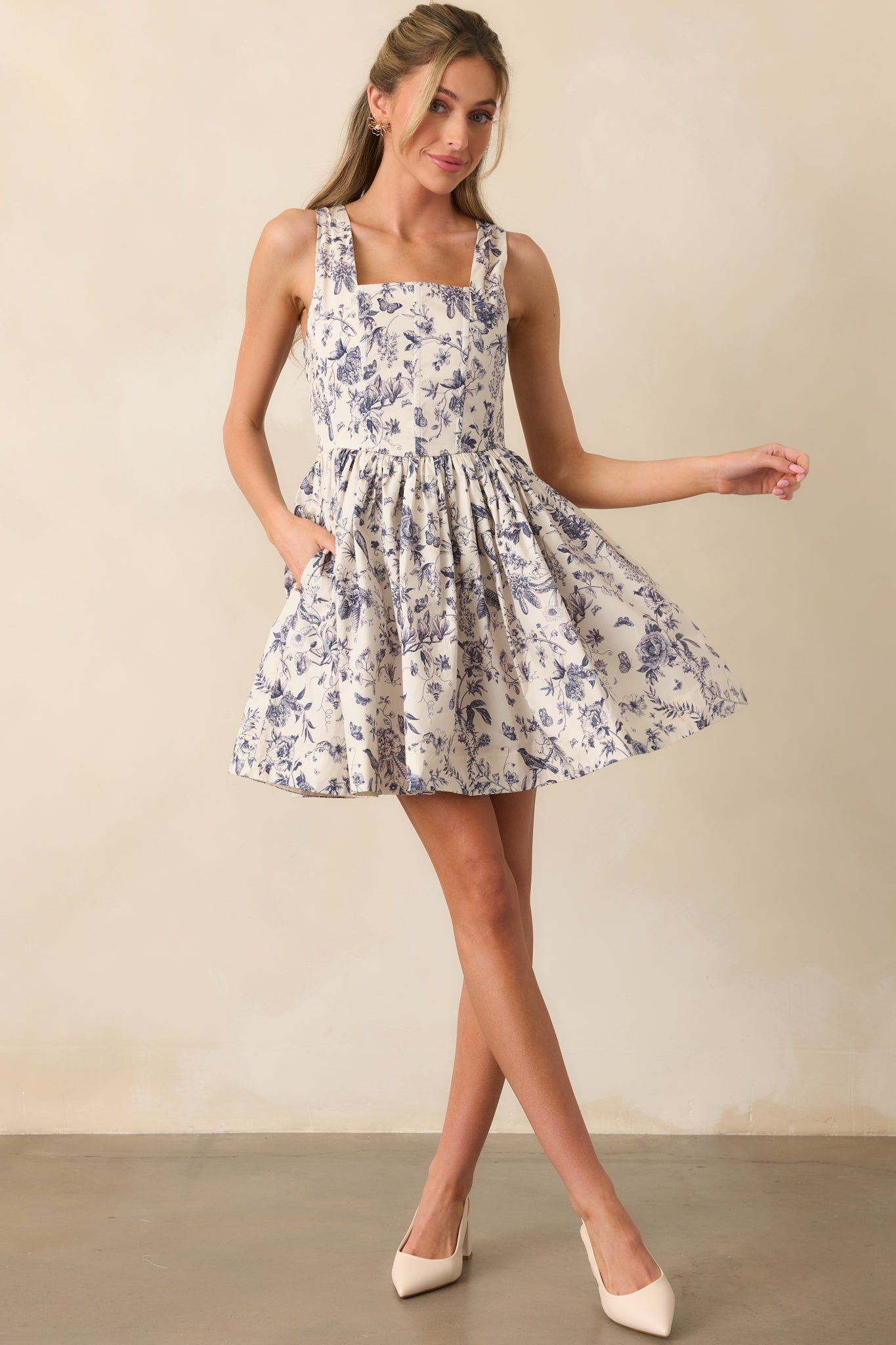 Ash blue mini dress with floral toile print, shown in full length to highlight the square neckline and pleated skirt.