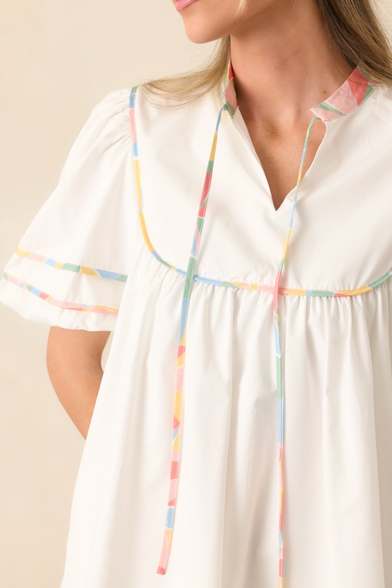 Close-up of the floral trim and textured fabric near the neckline and sleeve, emphasizing stitching and tassel detail.