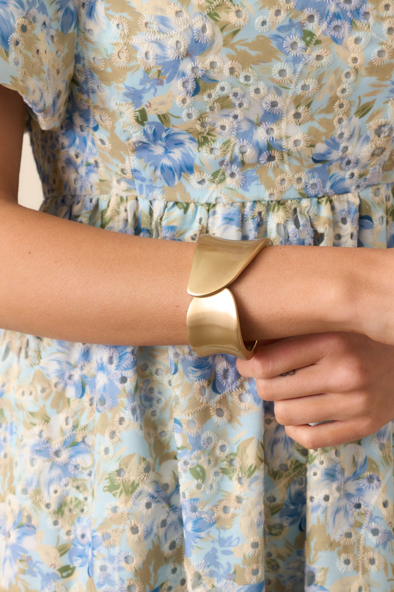 Zoomed-in view of the gold cuff bracelet highlighting its wide band and smooth oval shape.
