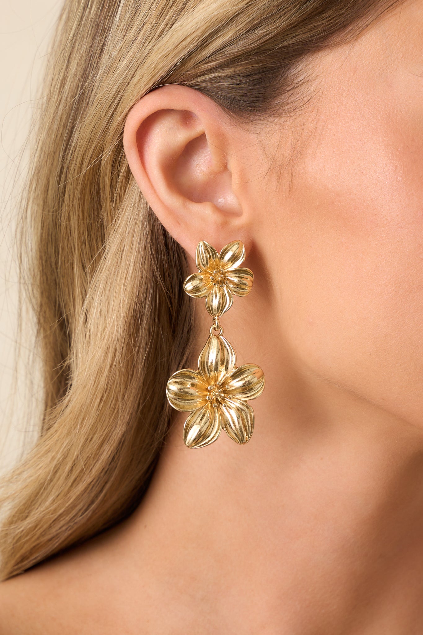 Close-up cropped view of the gold flower earrings showcasing the stud and drop design with intricate petal detailing.