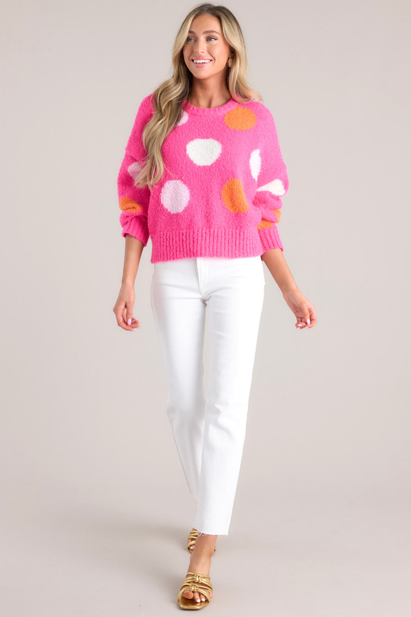 Front view of this hot pink polka dot sweater featuring a crew neckline, dropped shoulders, a ribbed hemline and ribbed cuffed long sleeves.