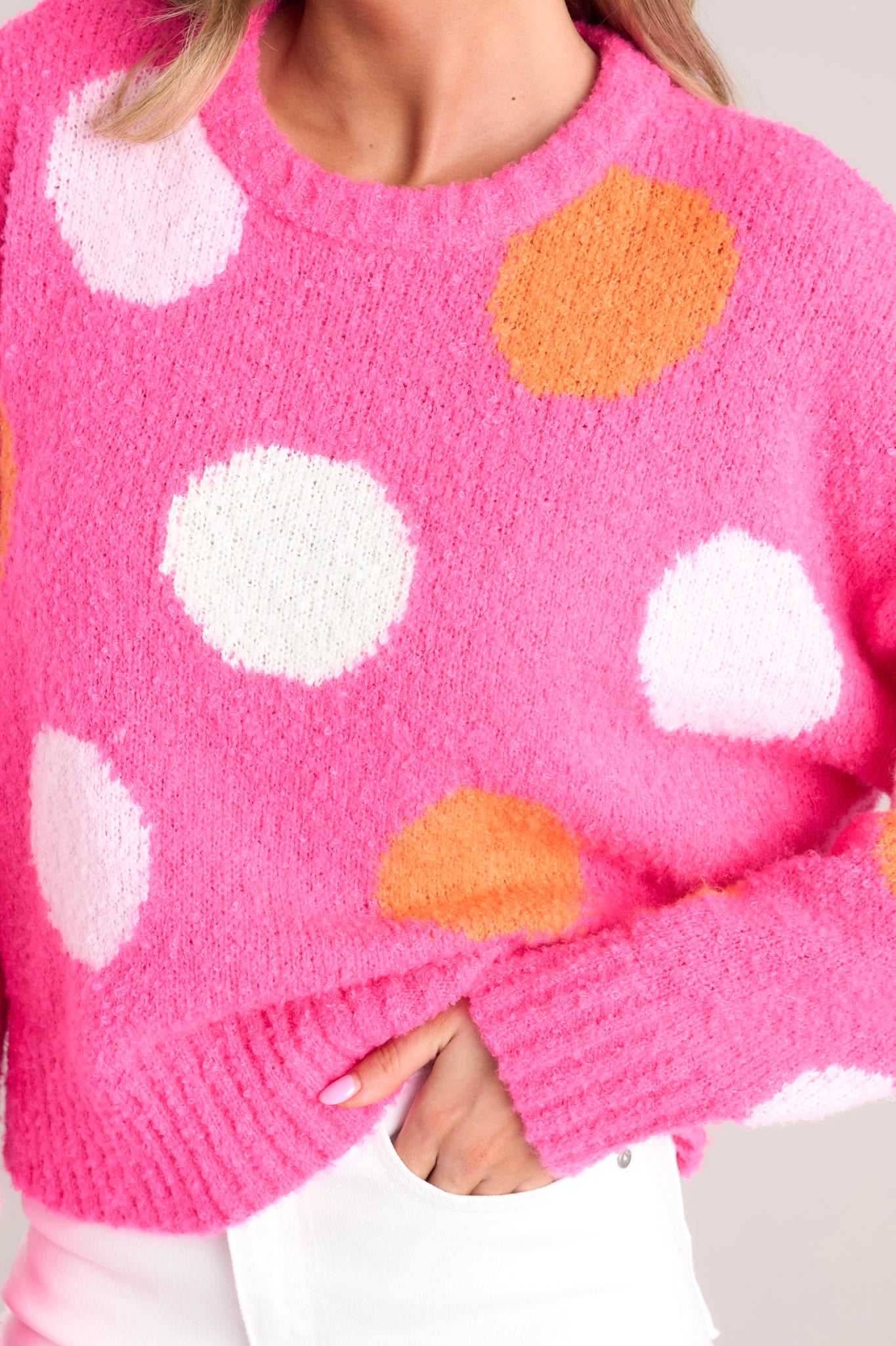 Close up detail shot of the white and orange polka dots on this hot pink sweater.