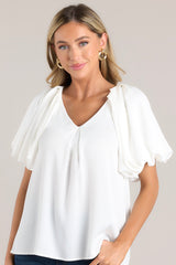 Front view of this top that features a v-neckline, pleated short sleeves, and elastic cuffs.