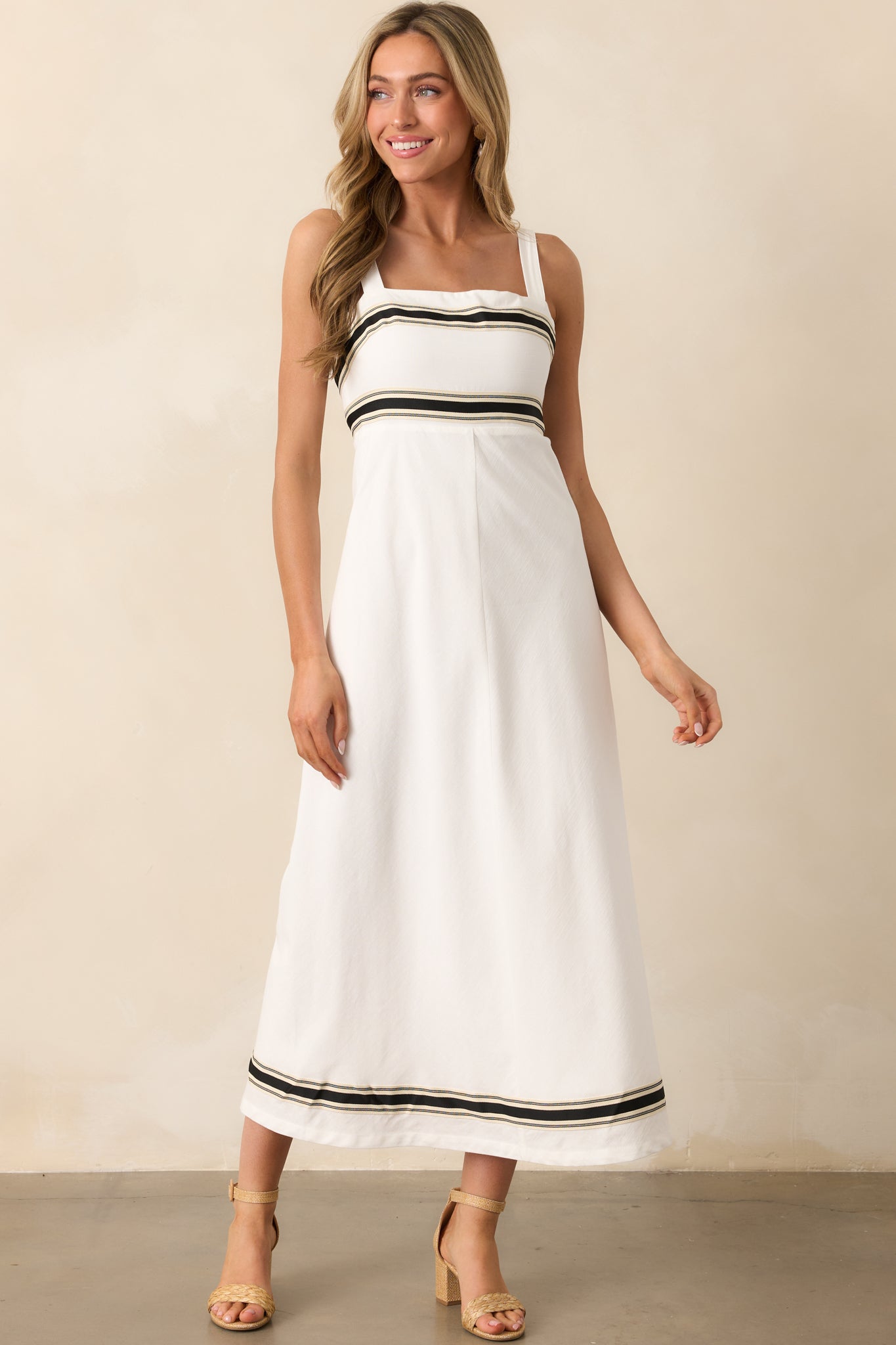 White midi dress with square neckline, adjustable straps, and black contrast trim detailing along the edges.