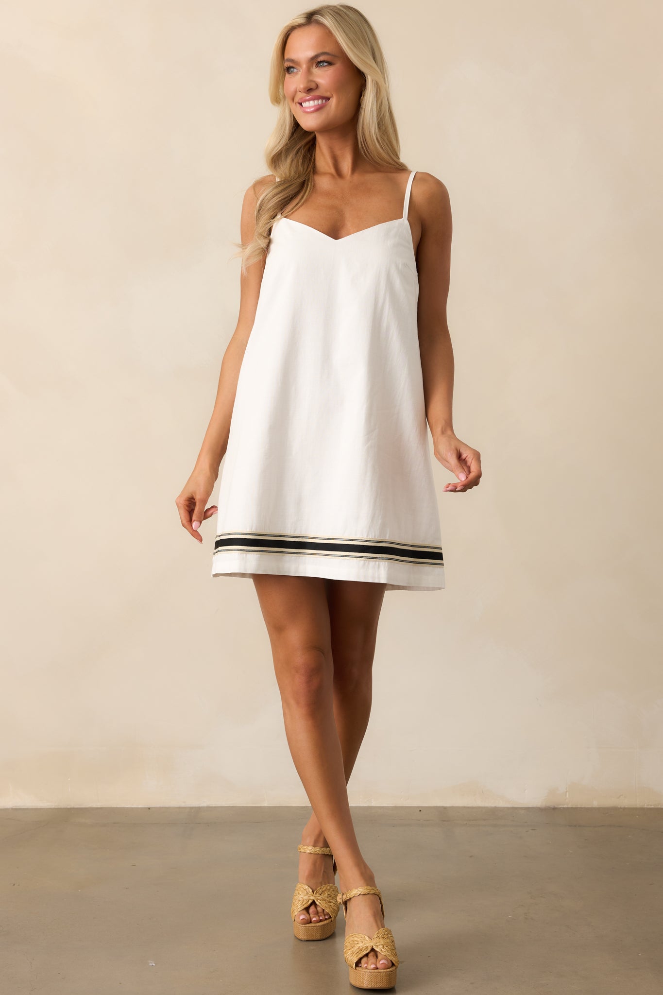 White mini dress with V-neckline, adjustable spaghetti straps, and a relaxed fit, shown in full-length view.