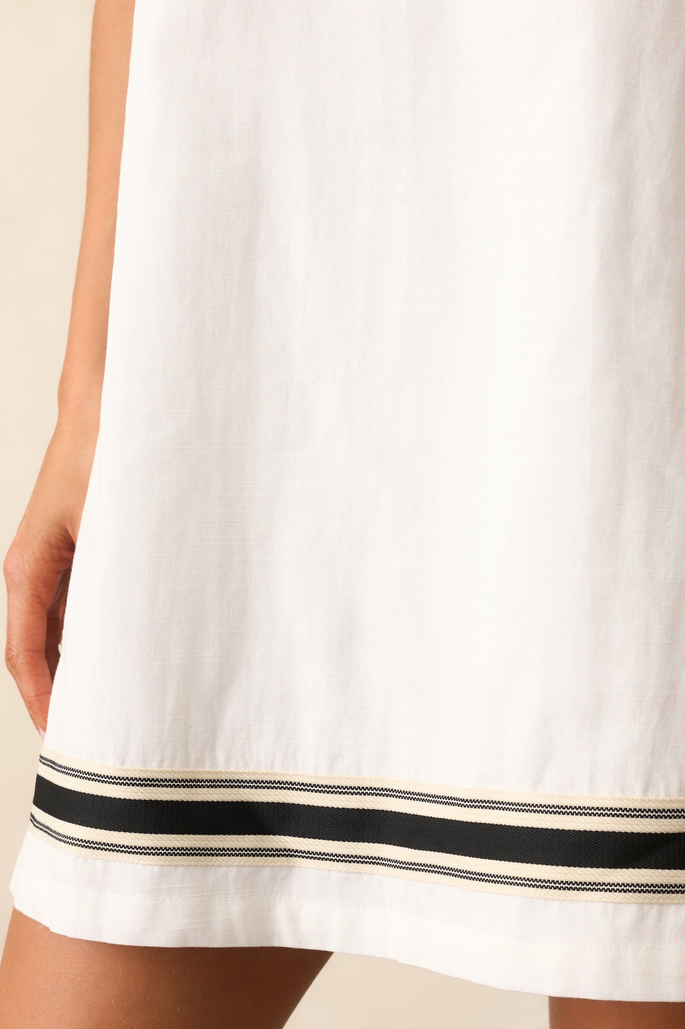 shot of the bottom hem, focusing on the black contrast trim and stitching against the white fabric.