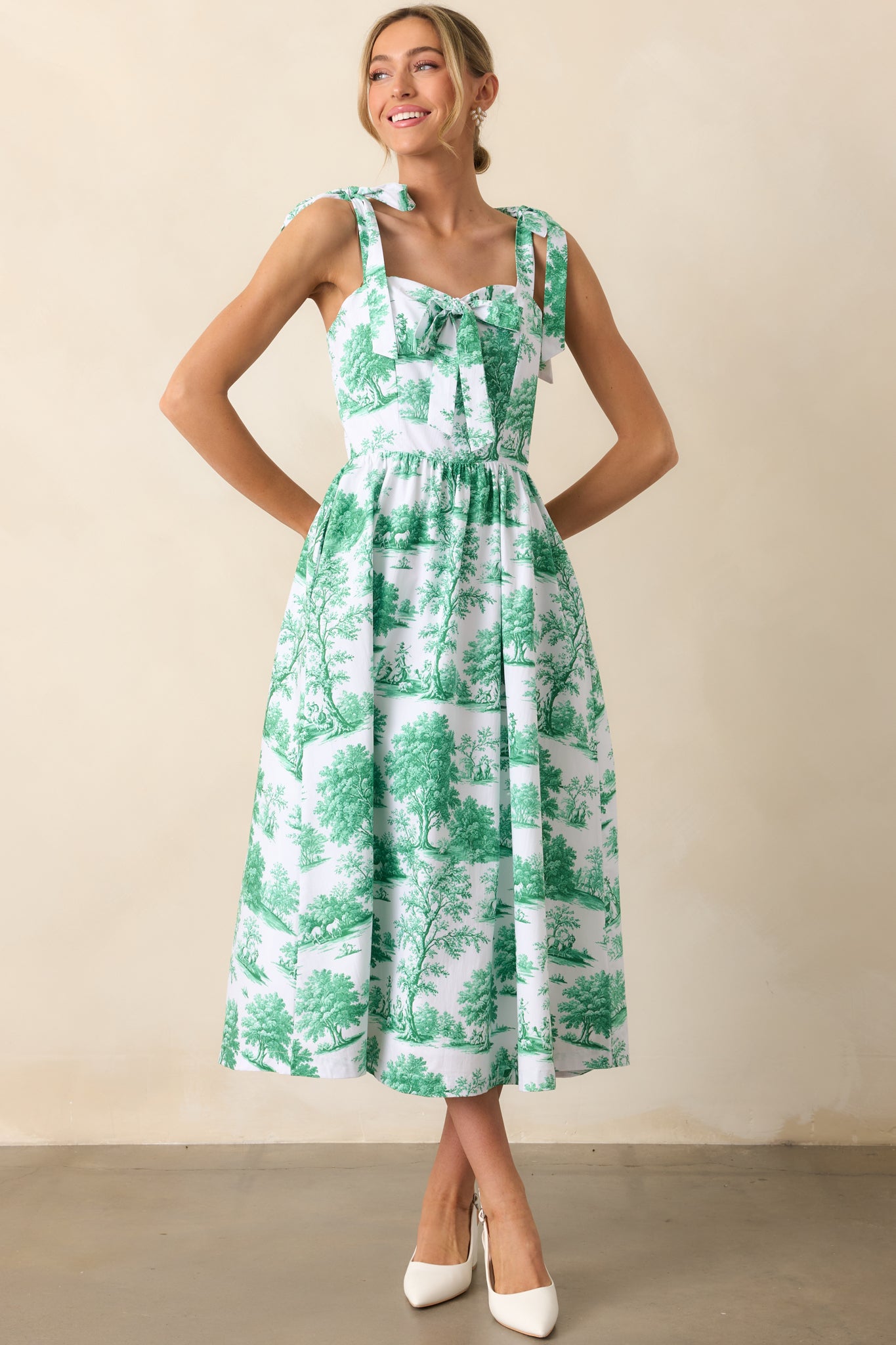 An eden green midi dress with adjustable self-tie bow straps, a sweetheart neckline, and a center bow detail for a charming touch.
